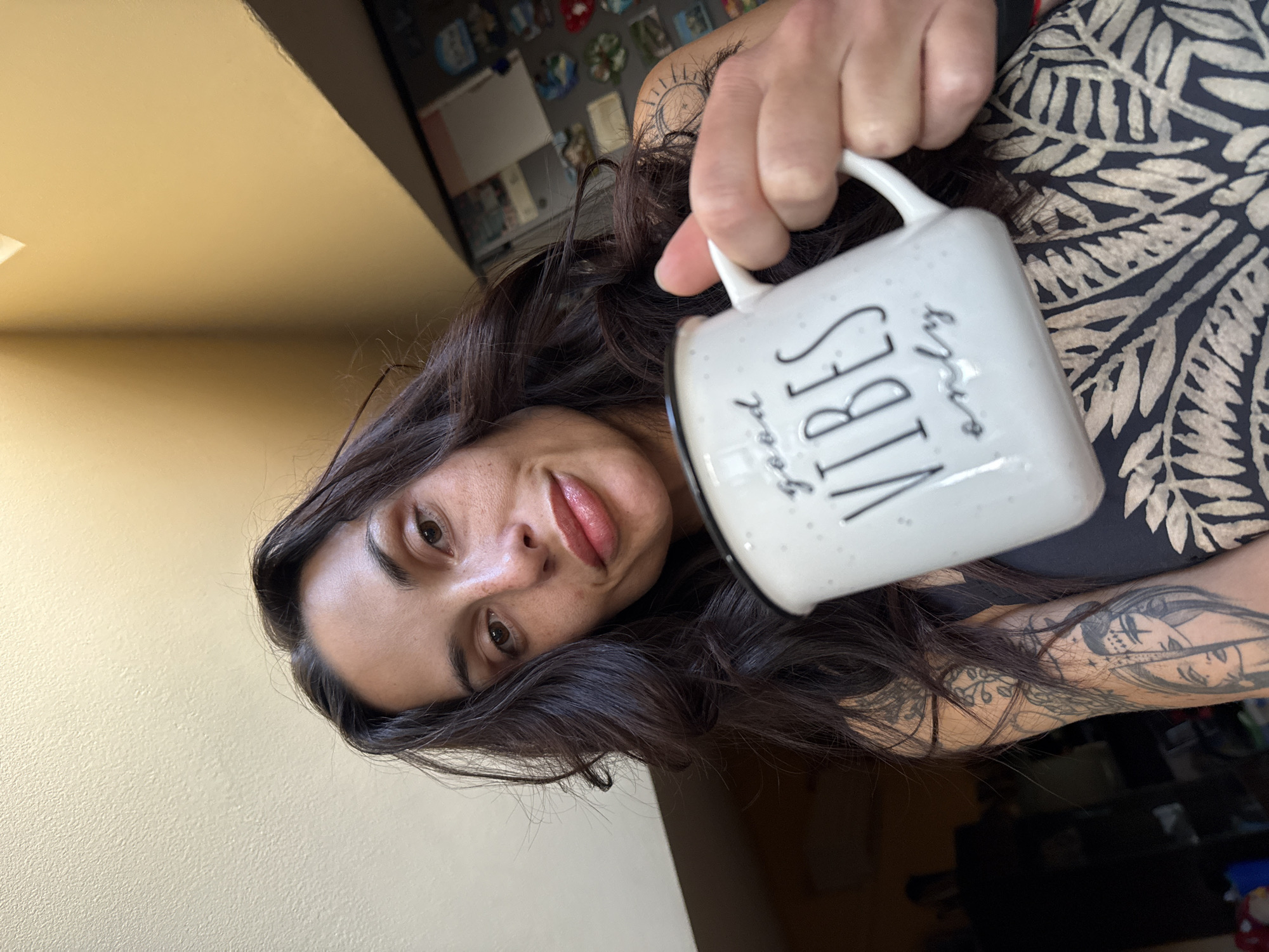 Woman with tattoos holds inspirational mug in early morning Bulgaria
