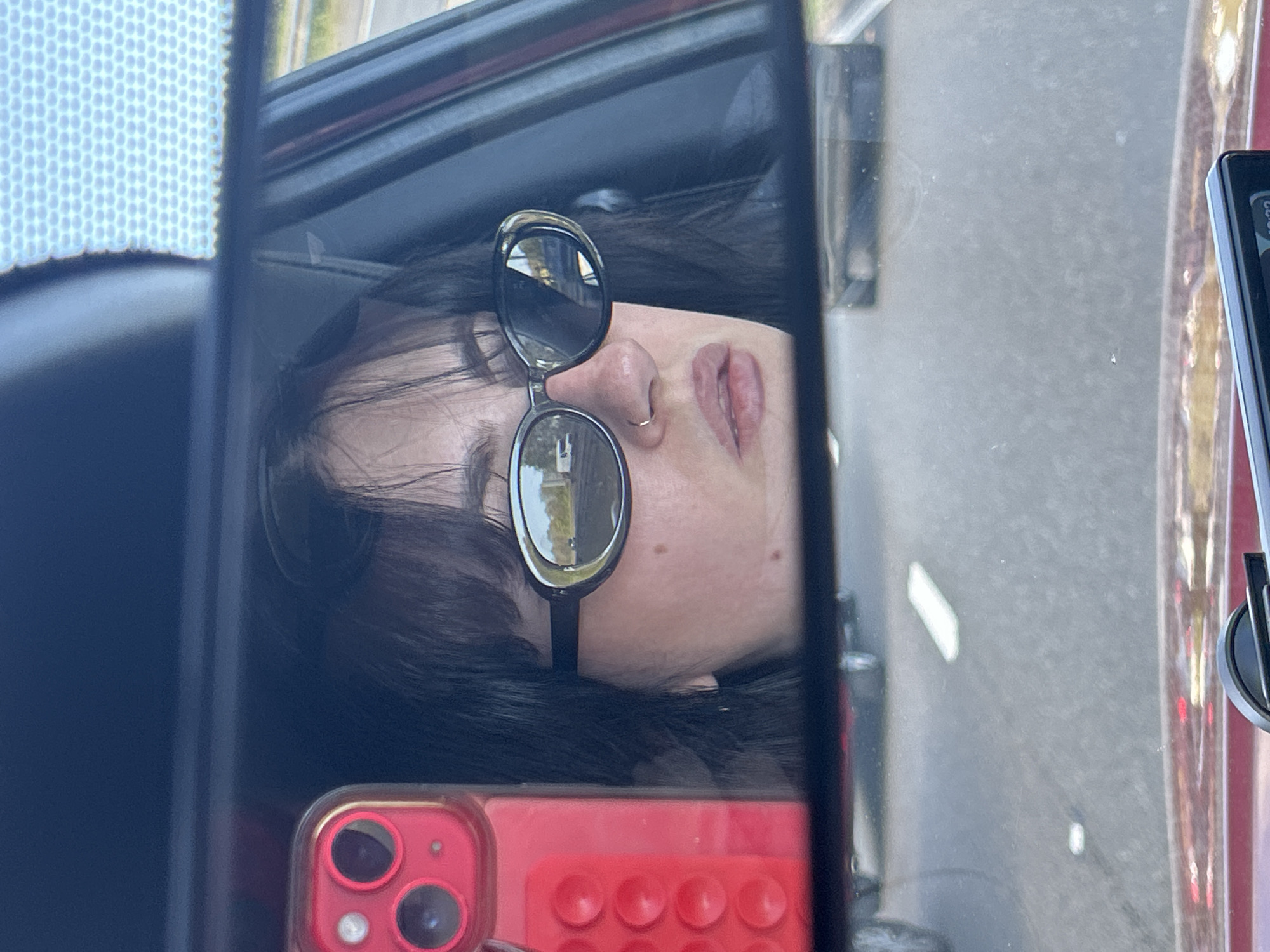 Person with red phone reflected in car window