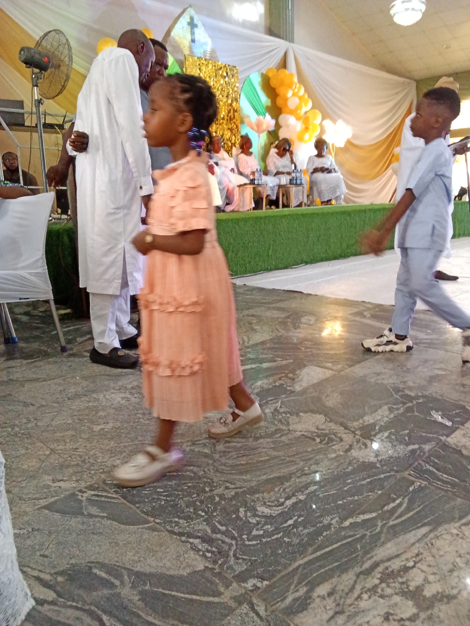 Formal indoor celebration with speeches, traditional dress, and decorated hall