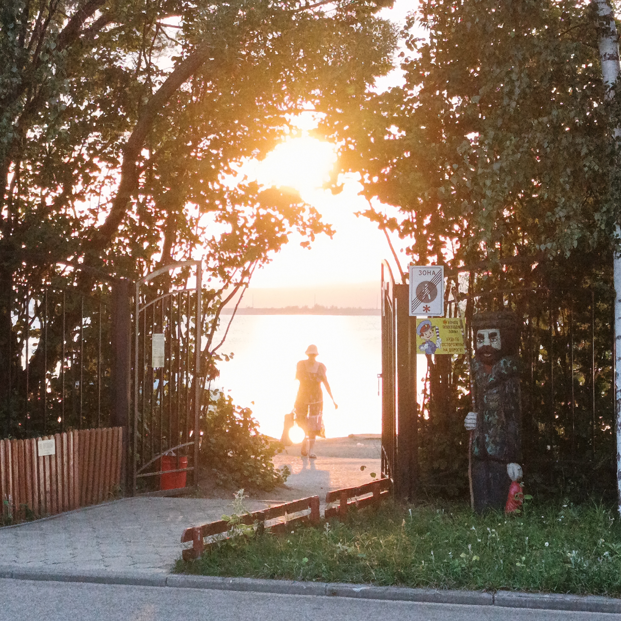 Silhouetted figure walks toward sunset through arched gateway