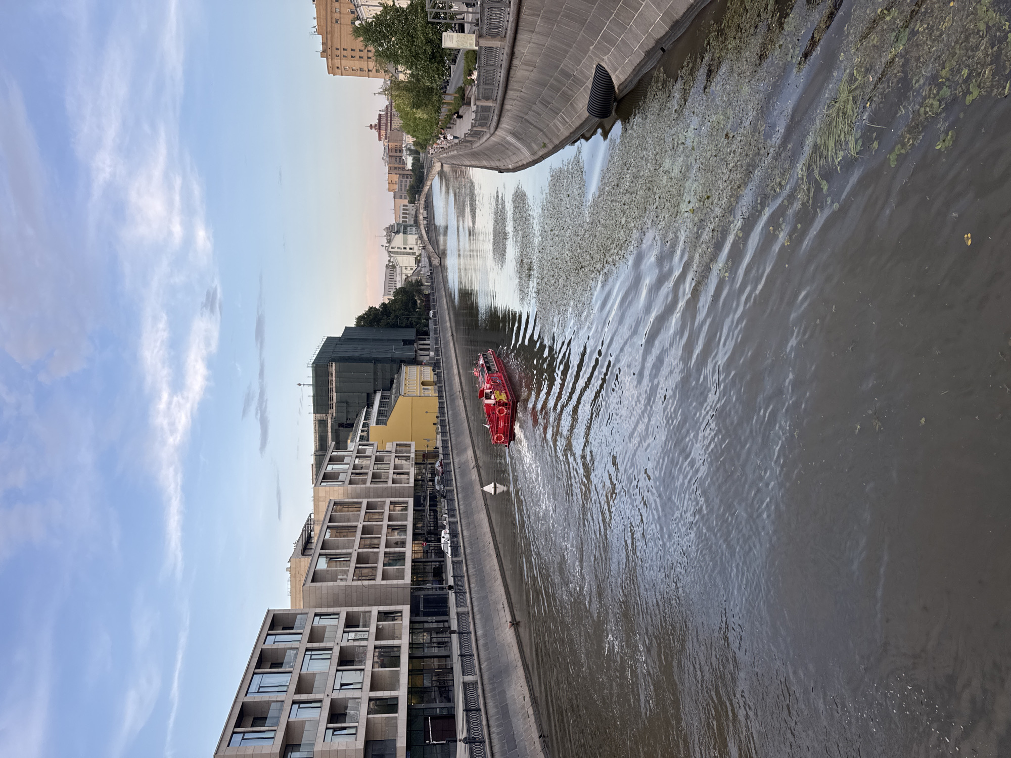 Red boat, iron gates, and city streets on a cloudy afternoon