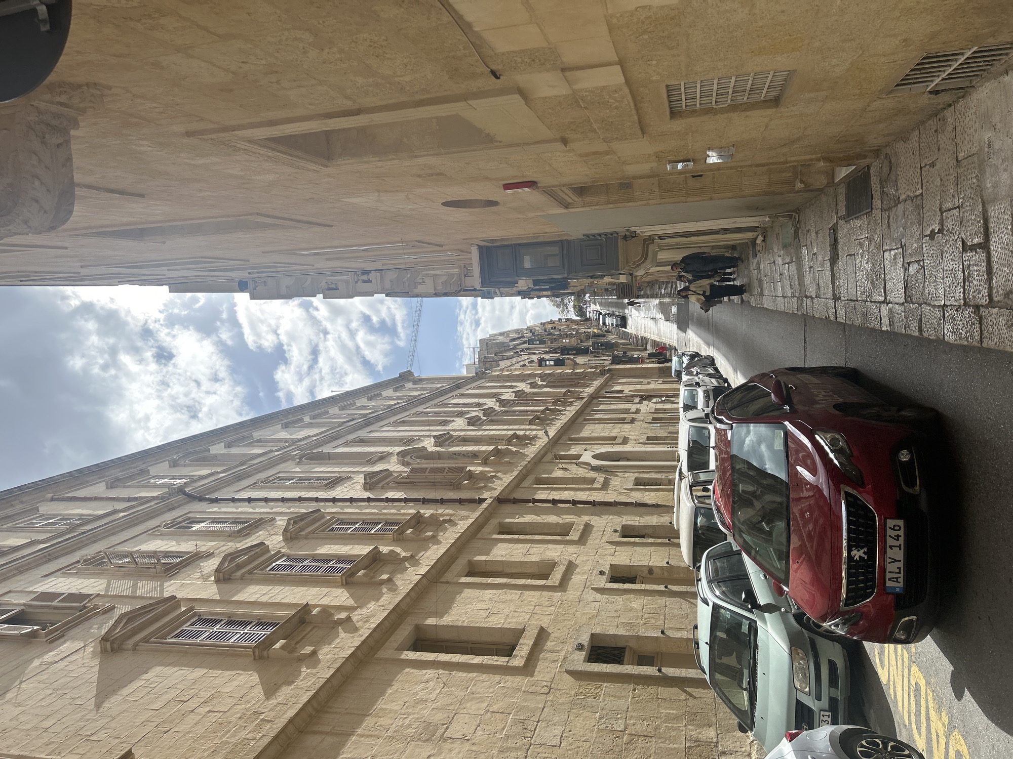 Historic stone buildings line narrow street in Valletta Malta