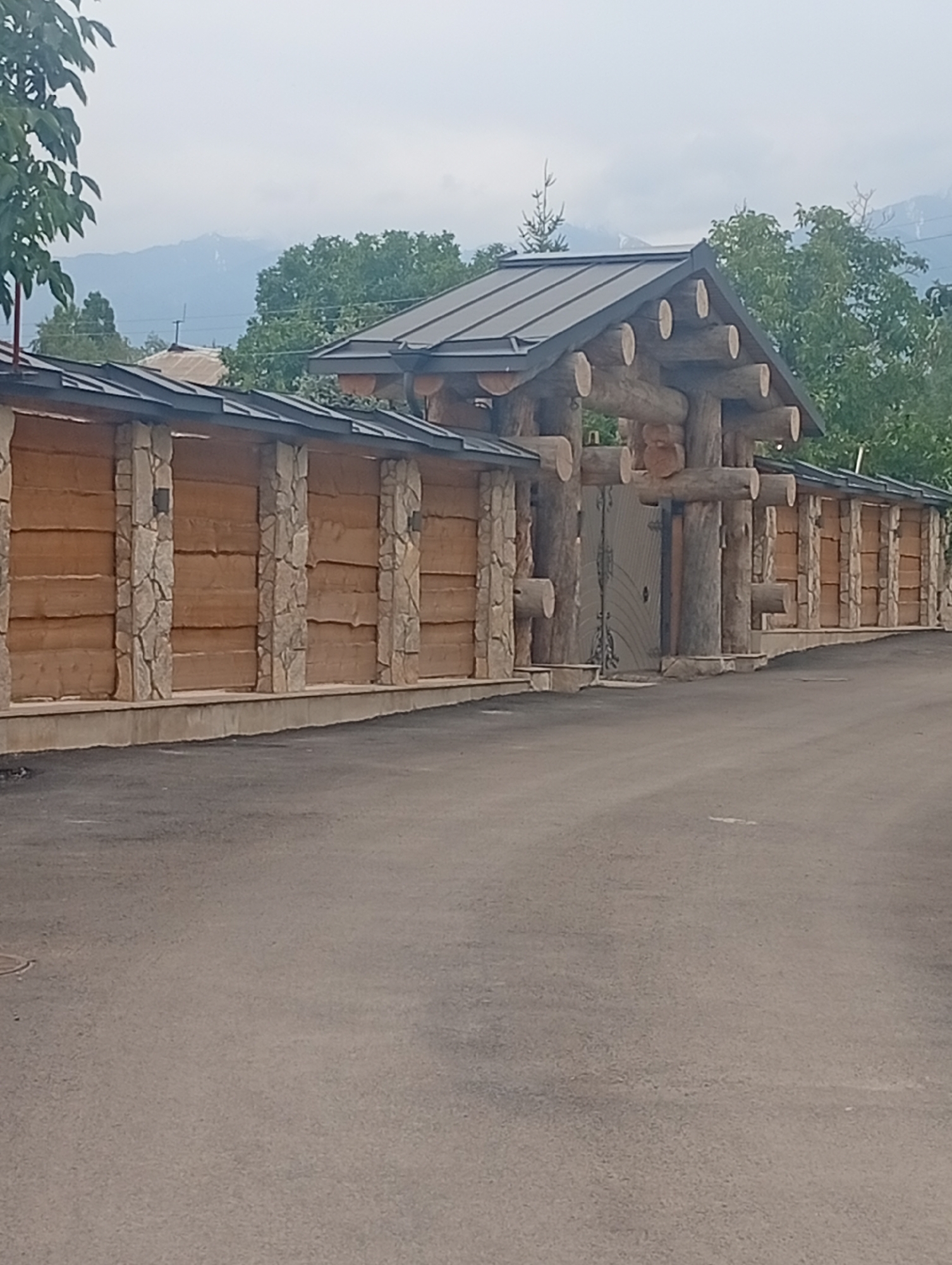 Rural Kyrgyz valley: gates, mountain views, and a littered stream