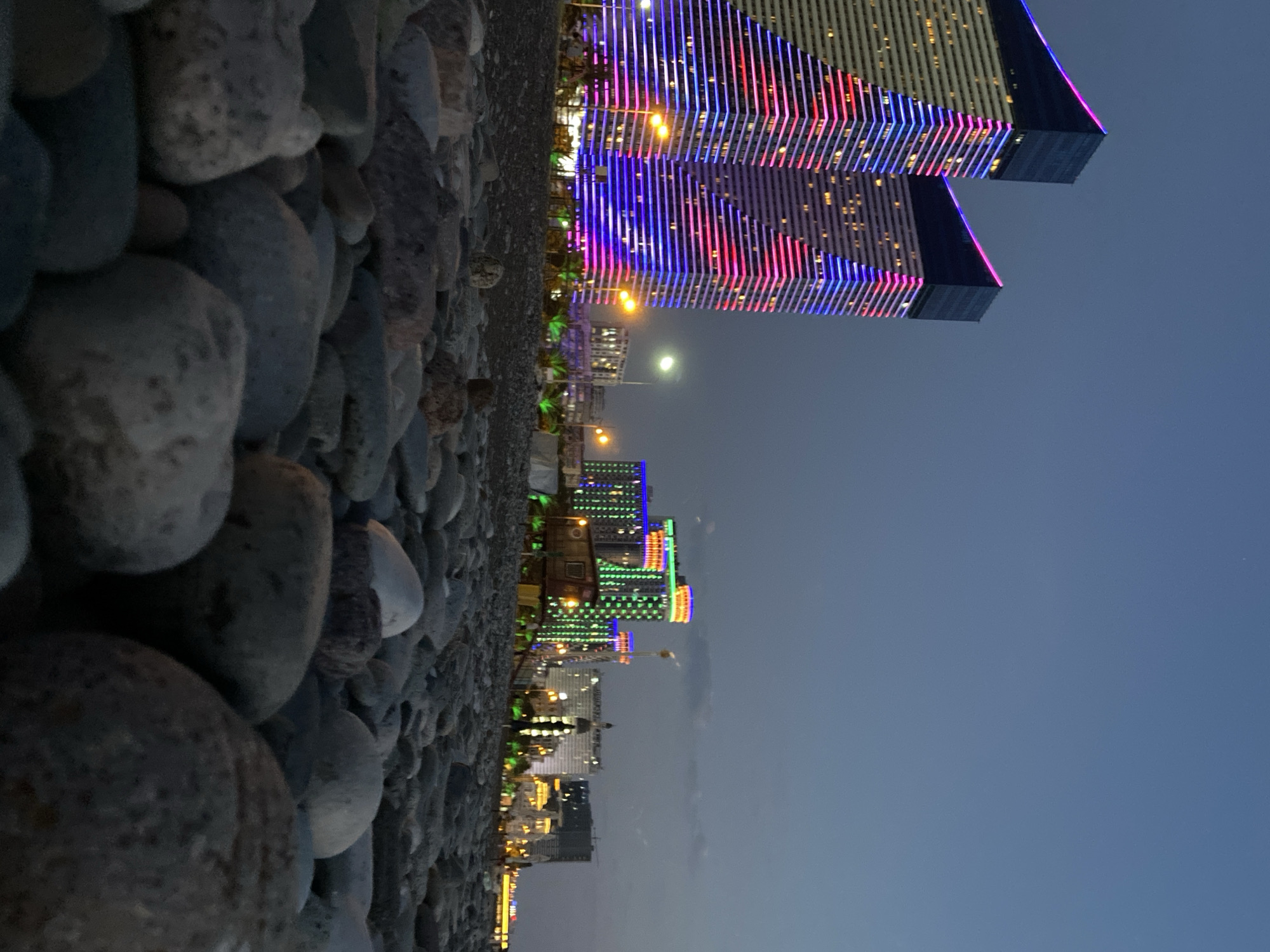 Batumi's pebble shore and glowing skyline at dusk