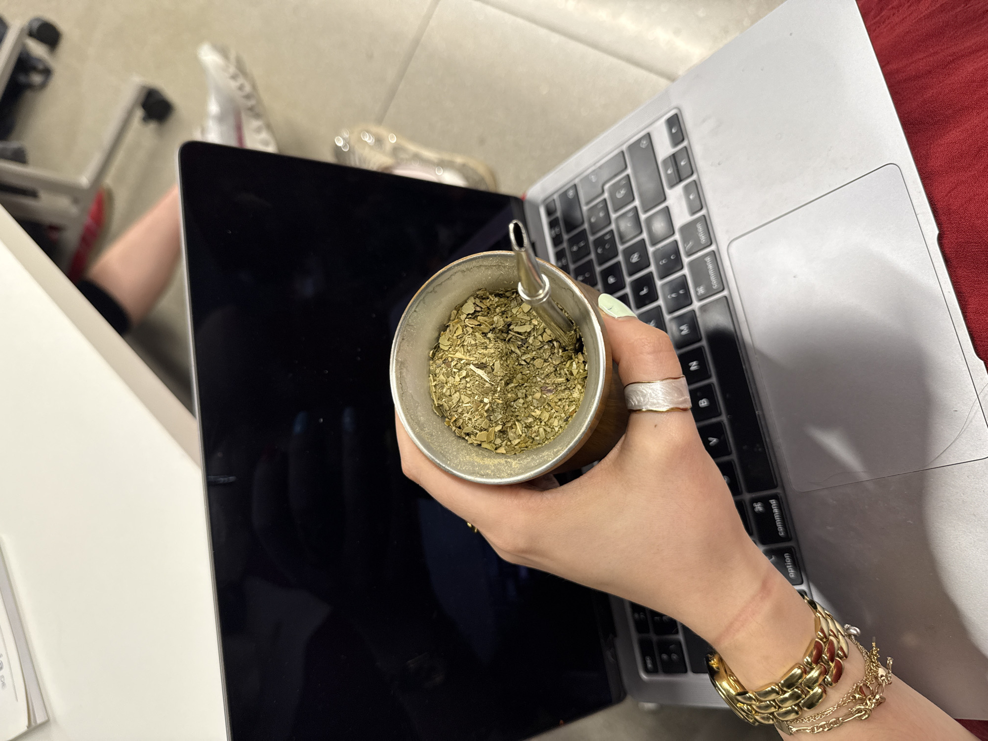 Person drinks traditional mate while using laptop in Mexico City