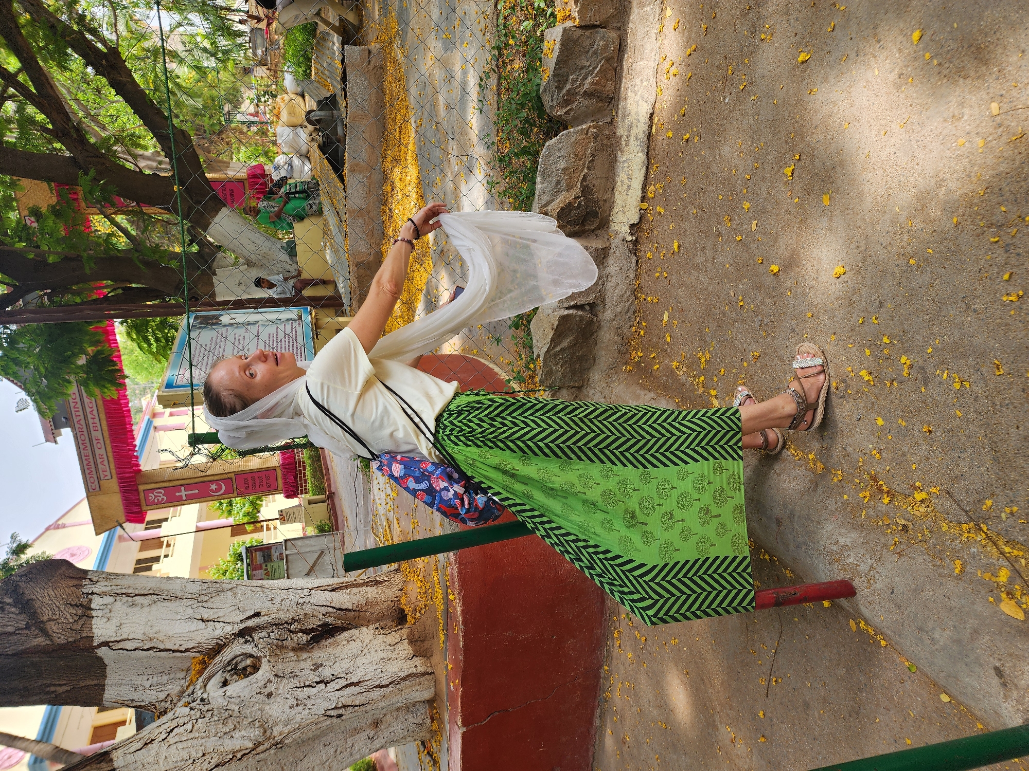 Woman in patterned green skirt observed outdoors holding object