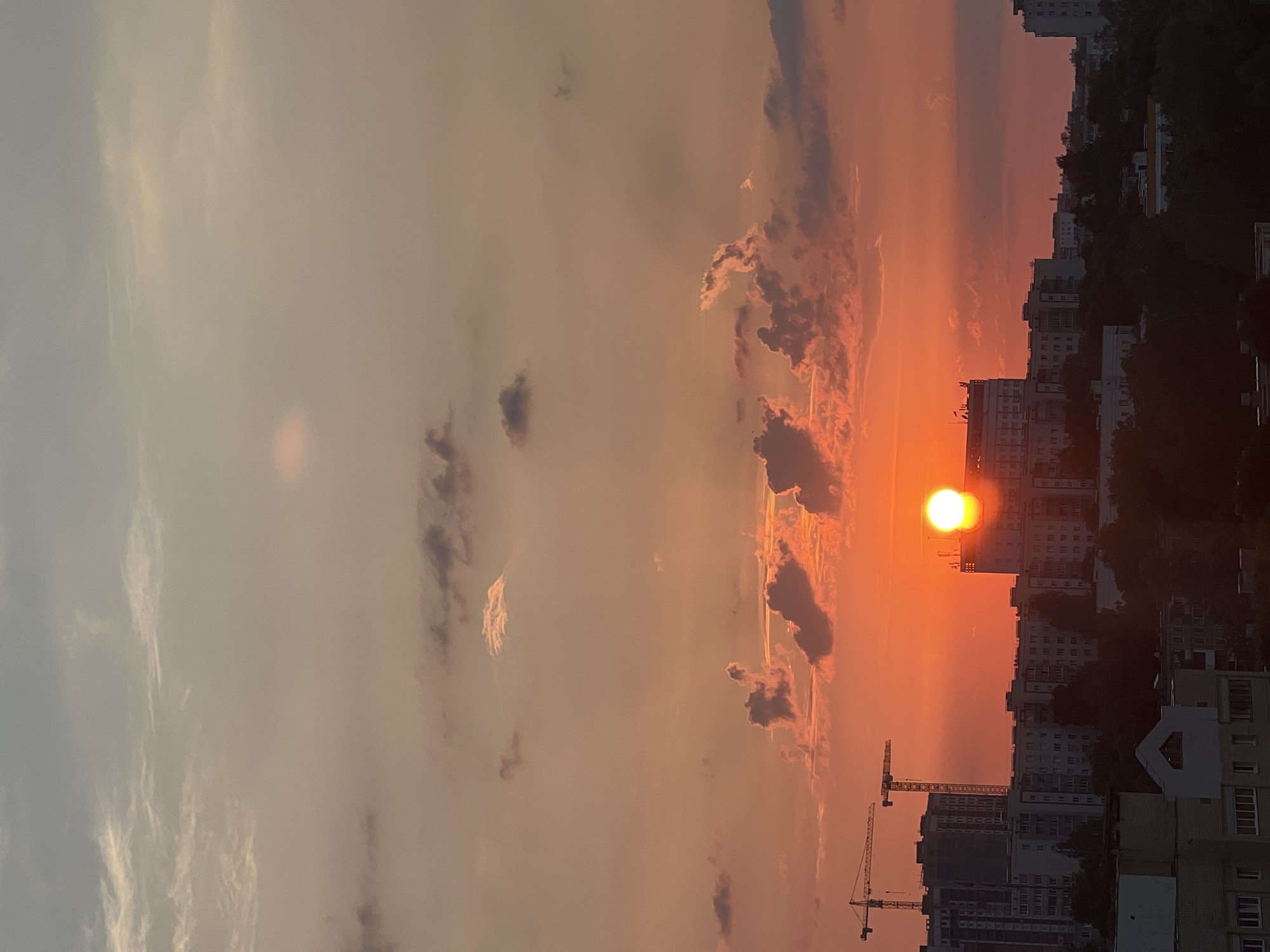 Minsk sunset, sun dipping behind city buildings