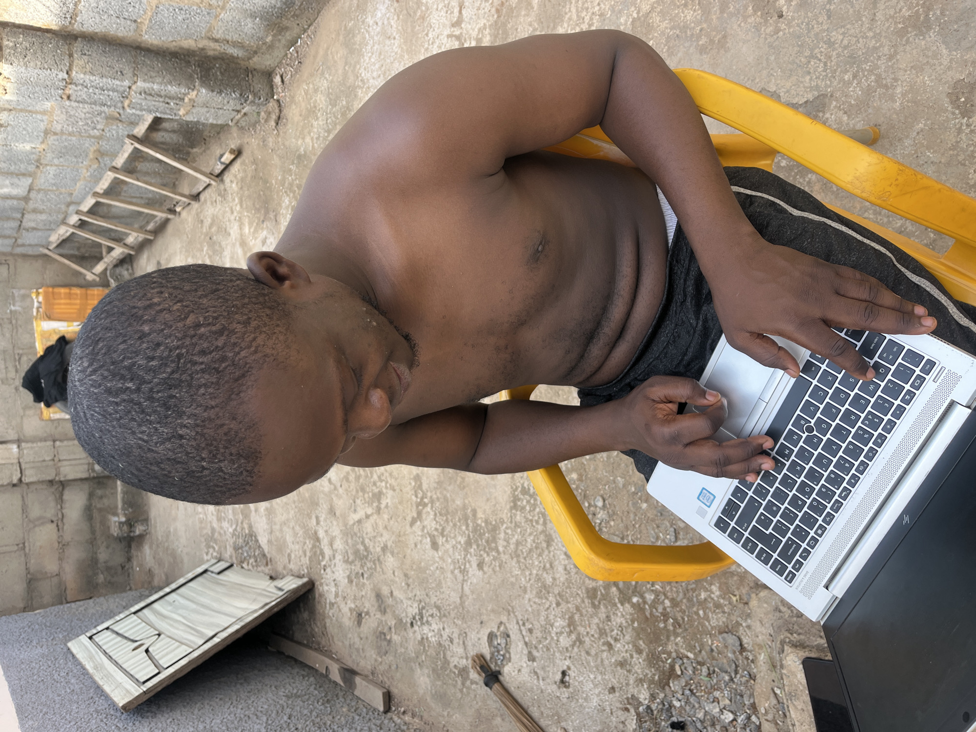 Man works on laptop outdoors in Abuja construction area