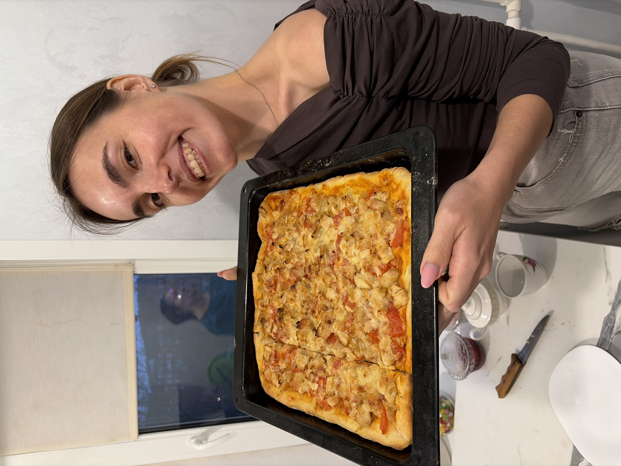 Woman displays homemade pizza in Sarapul kitchen