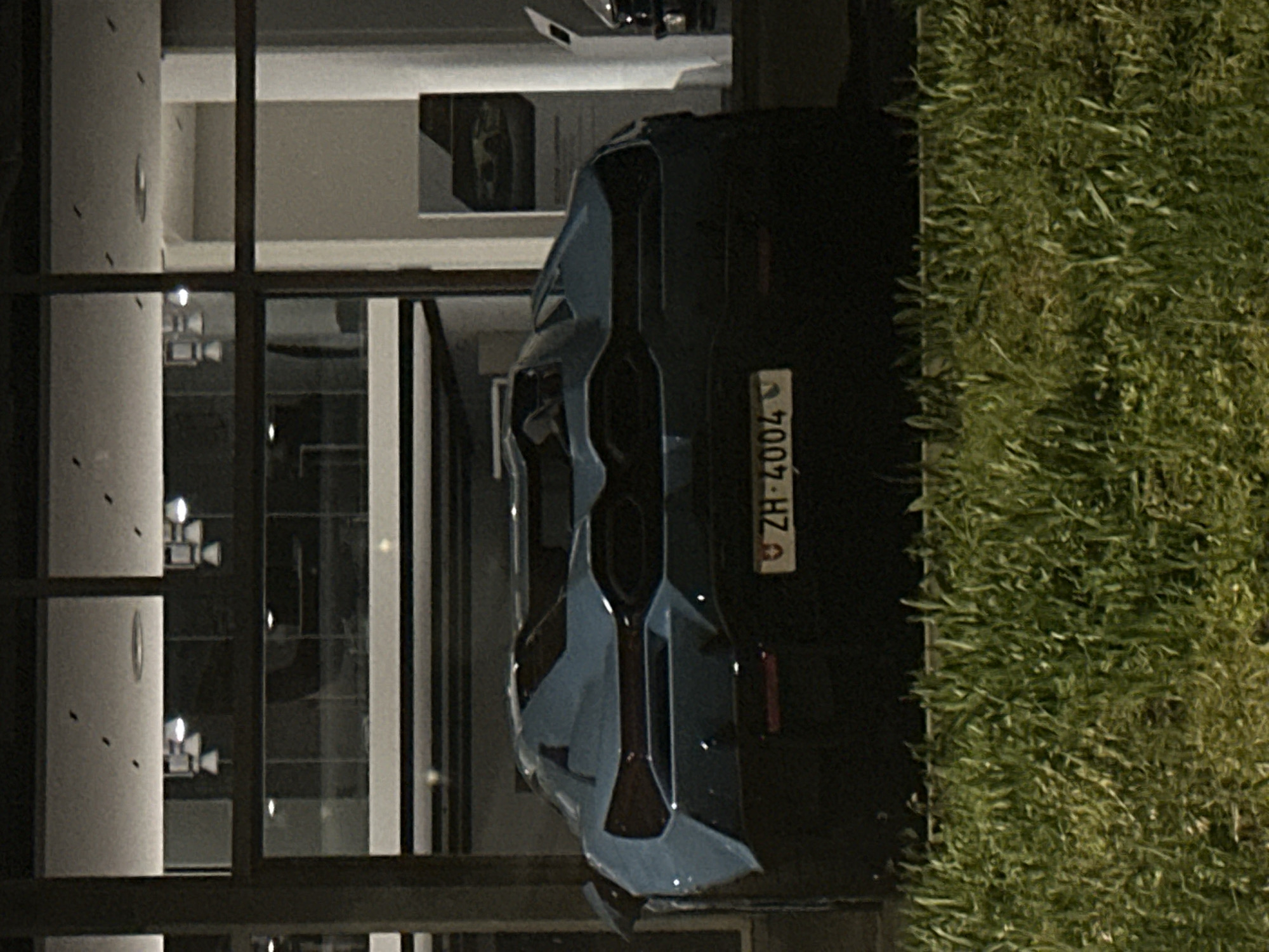 Blue BMW M4 parked near luxury dealership in Kloten