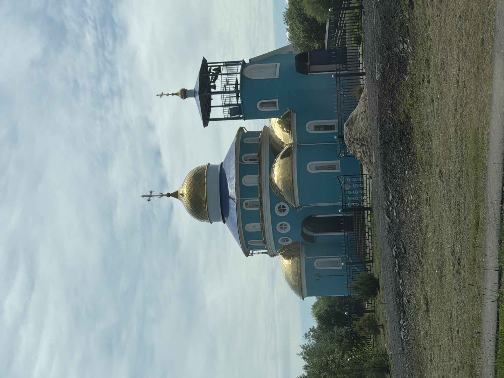 Boy pulls cart near turquoise church in Smidovich, Russia