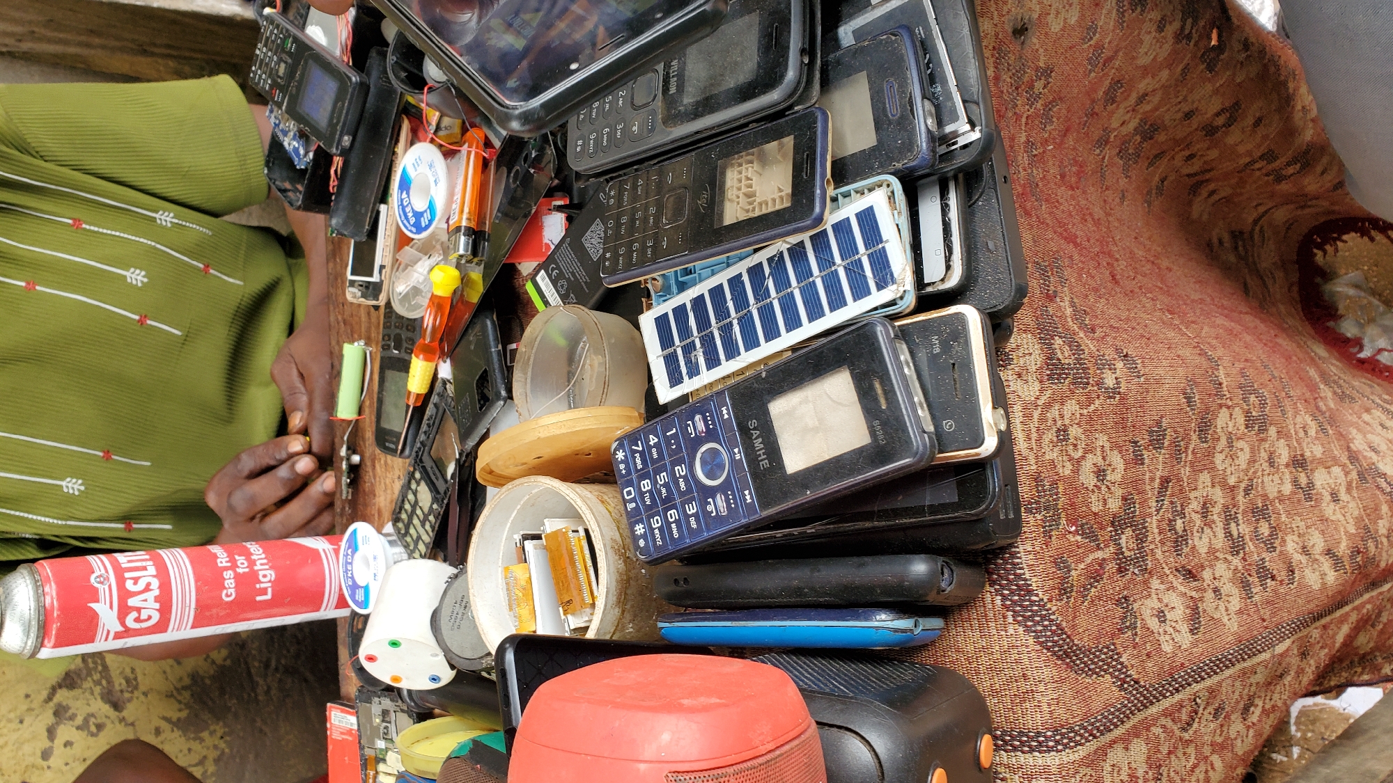 Street-side phone repair work at a Jalingo market stall