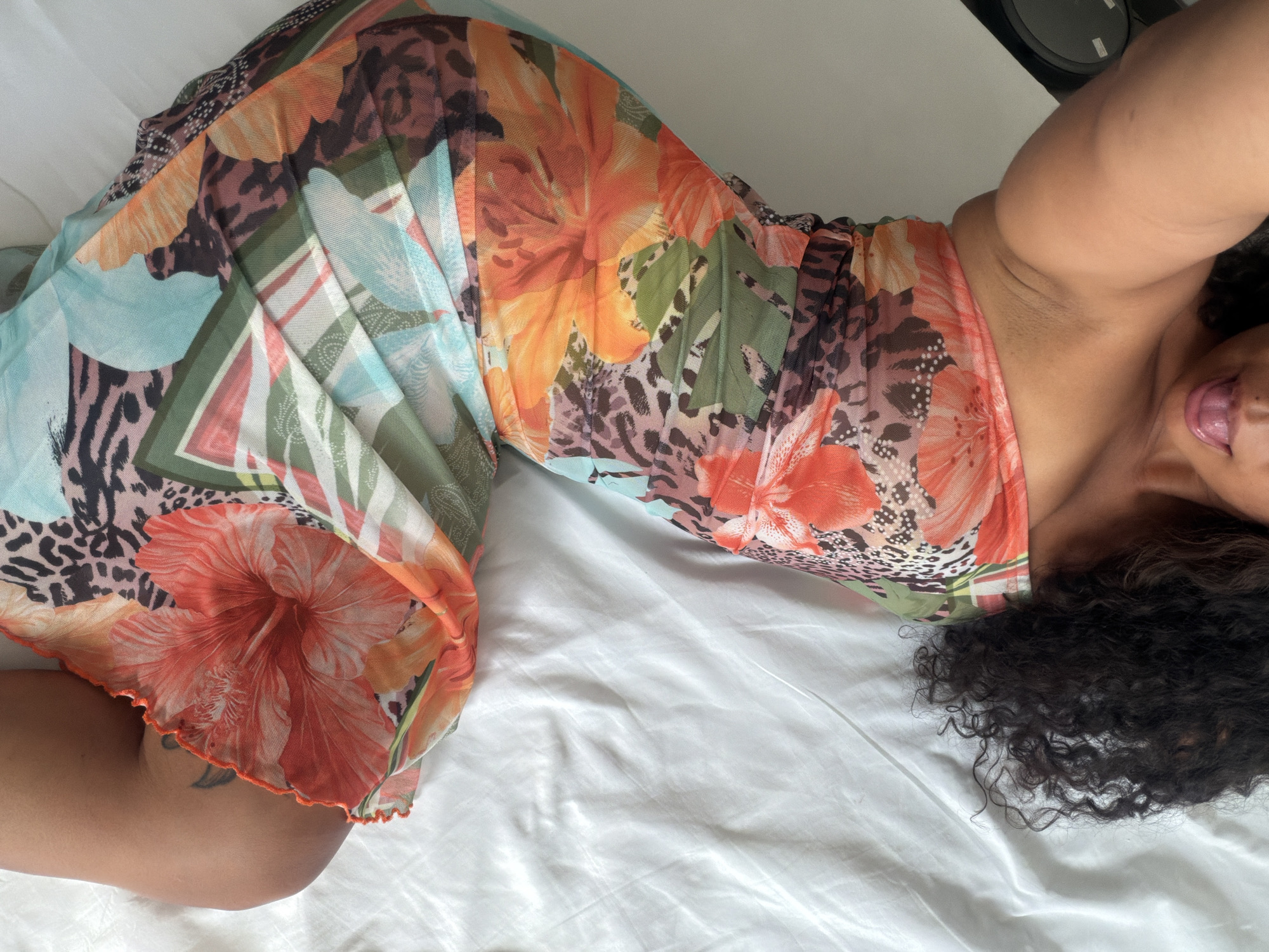 Woman in floral dress rests on bed in Barcelona