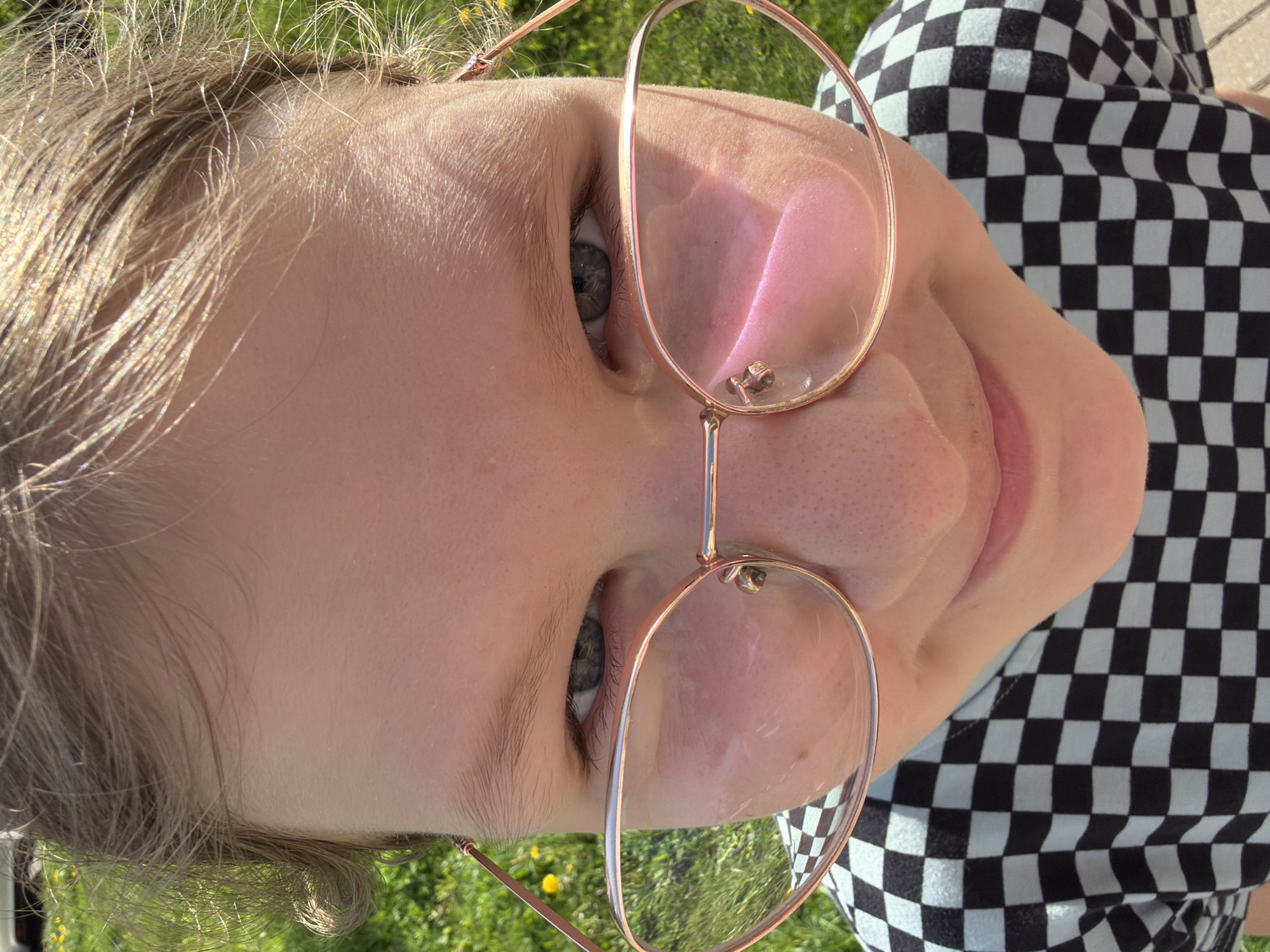 Woman in strawberry hoodie photographed applying makeup outdoors