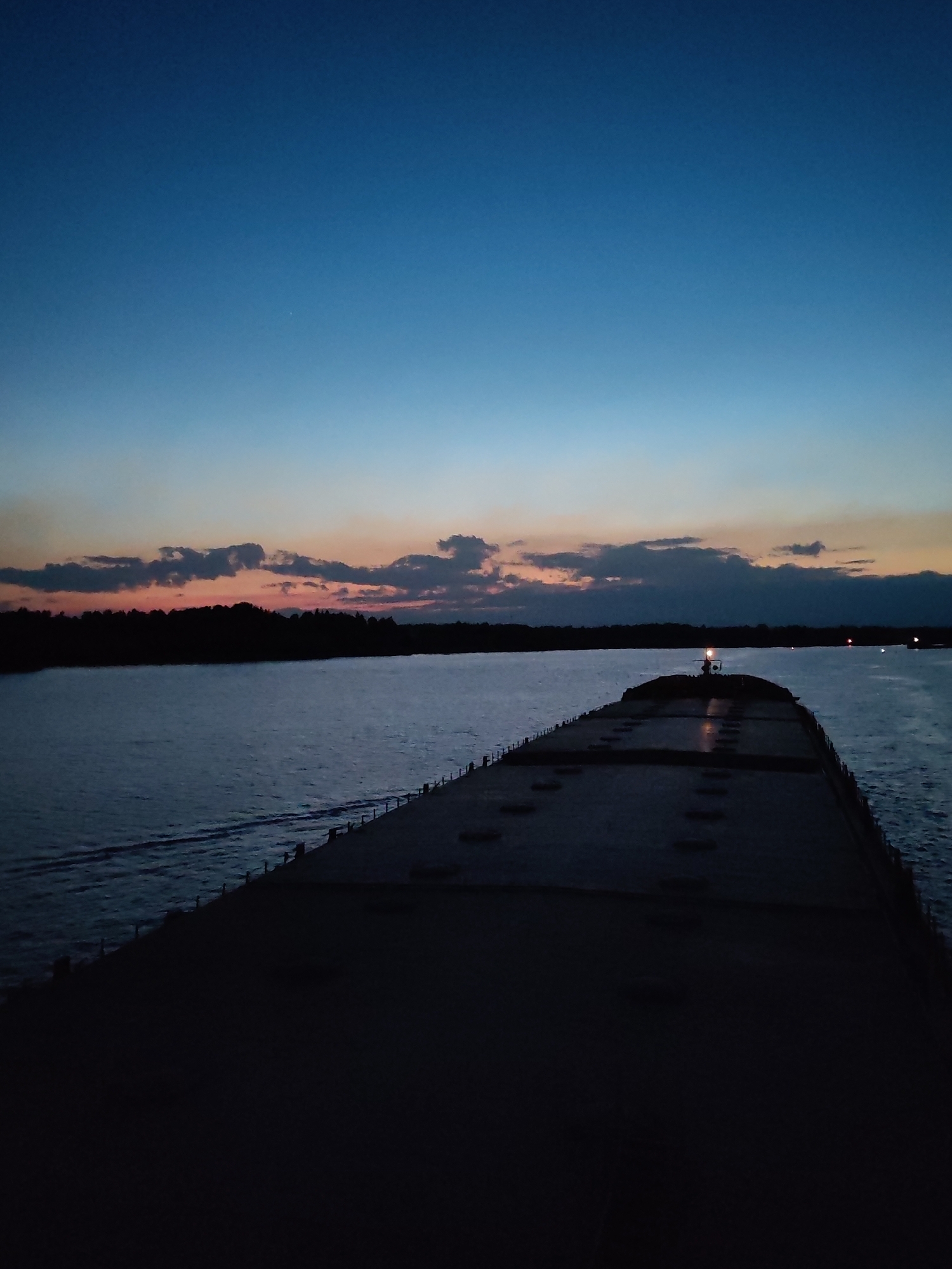 Nighttime waterway scenes show barge and illuminated cable-stayed bridge