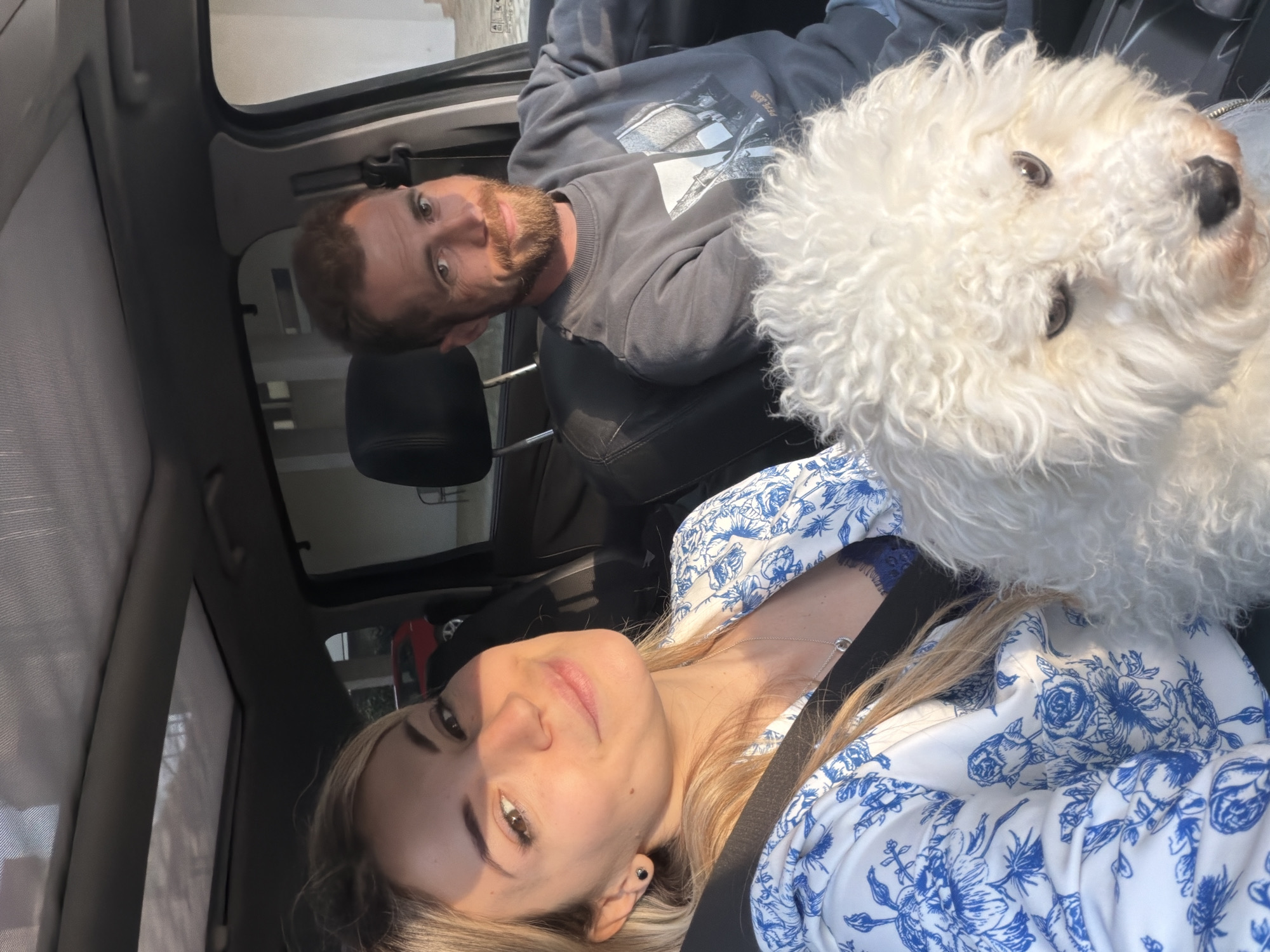 Couple travels with fluffy white dog through sunny Budva
