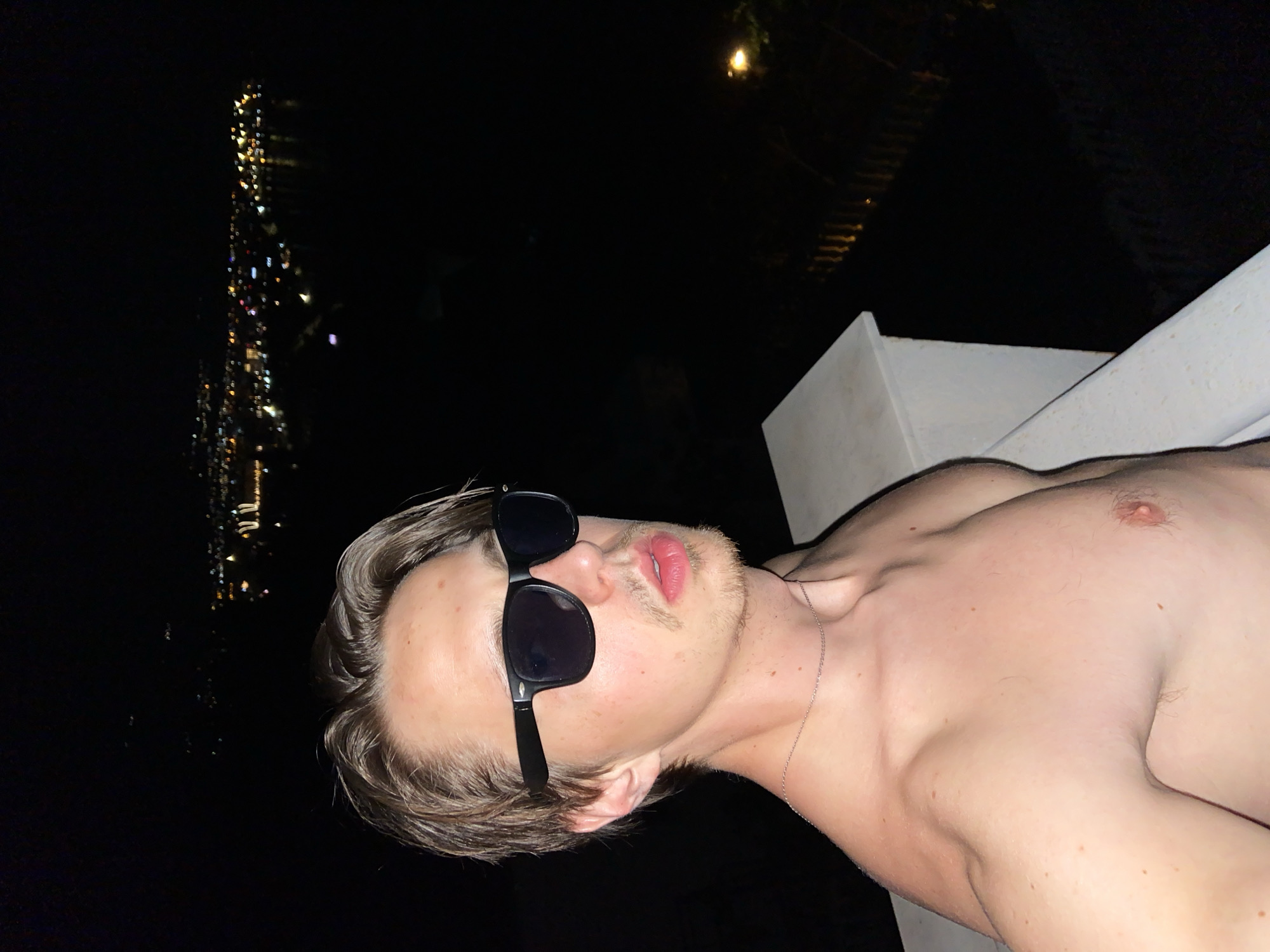 Man poses for nighttime photos on ledge in Šušanj