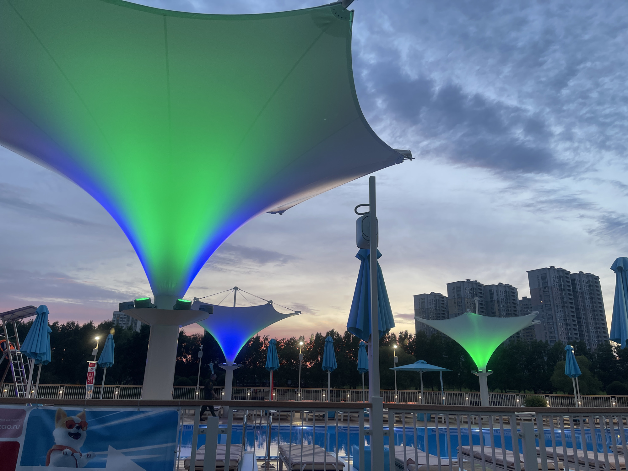 Moscow waterfront at dusk: pools, decks, and a summer sky