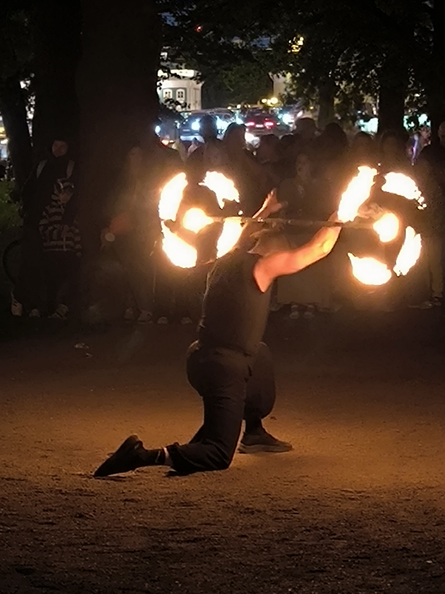 Fire performer juggles flames for outdoor crowd at night