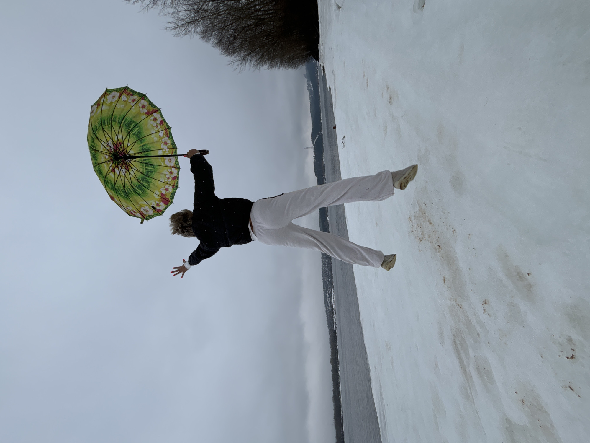 Person caught mid-air with umbrella on snowy ground in Russia