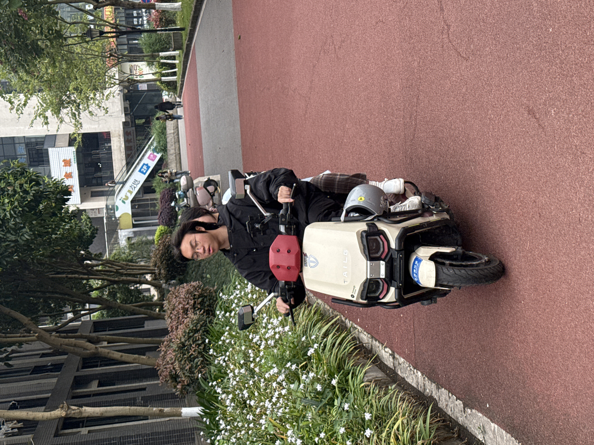Electric scooter rider pauses on red path in Jiangjin