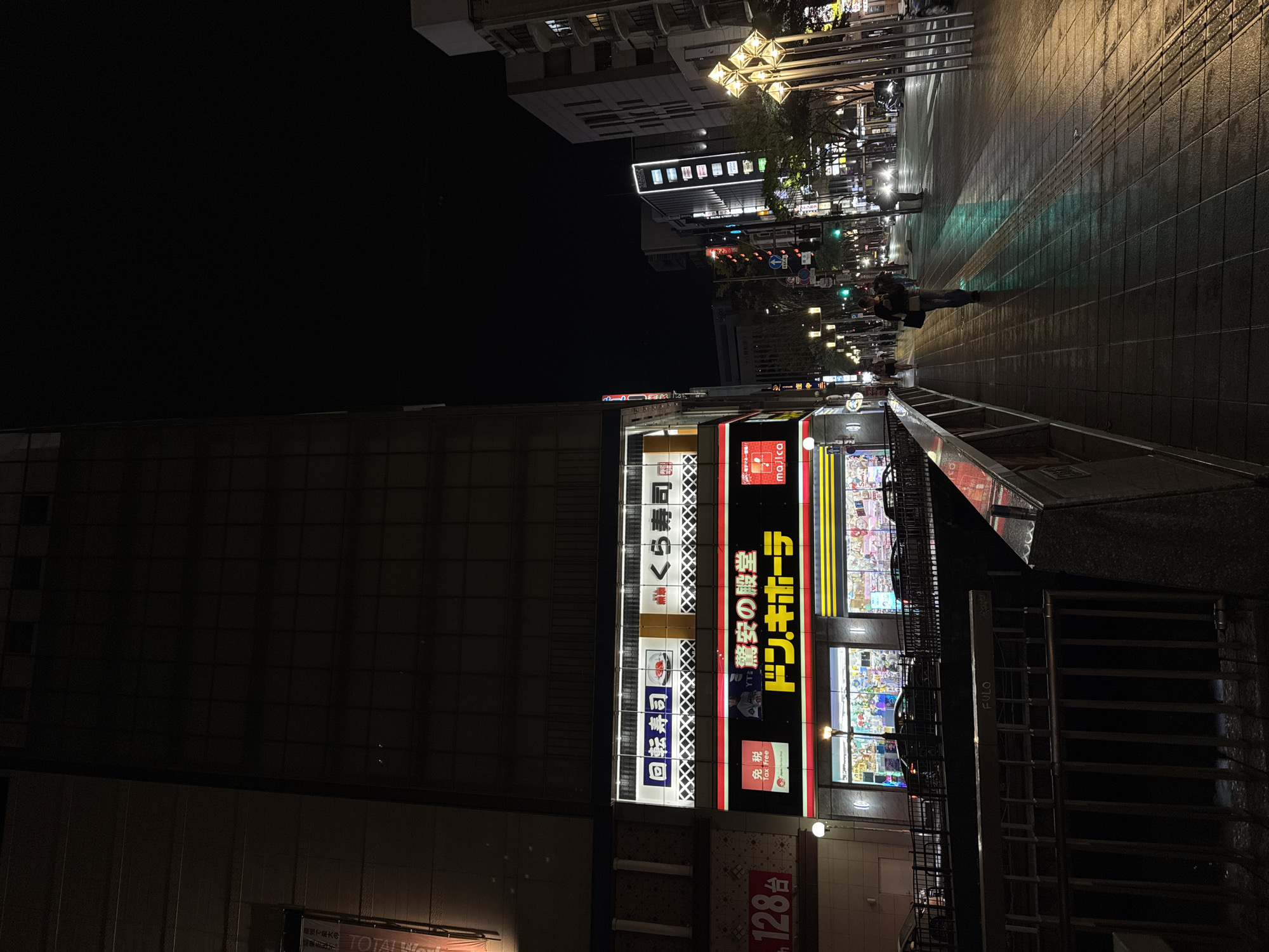 Wet nighttime street scene captured near Don Quijote in Fukuoka