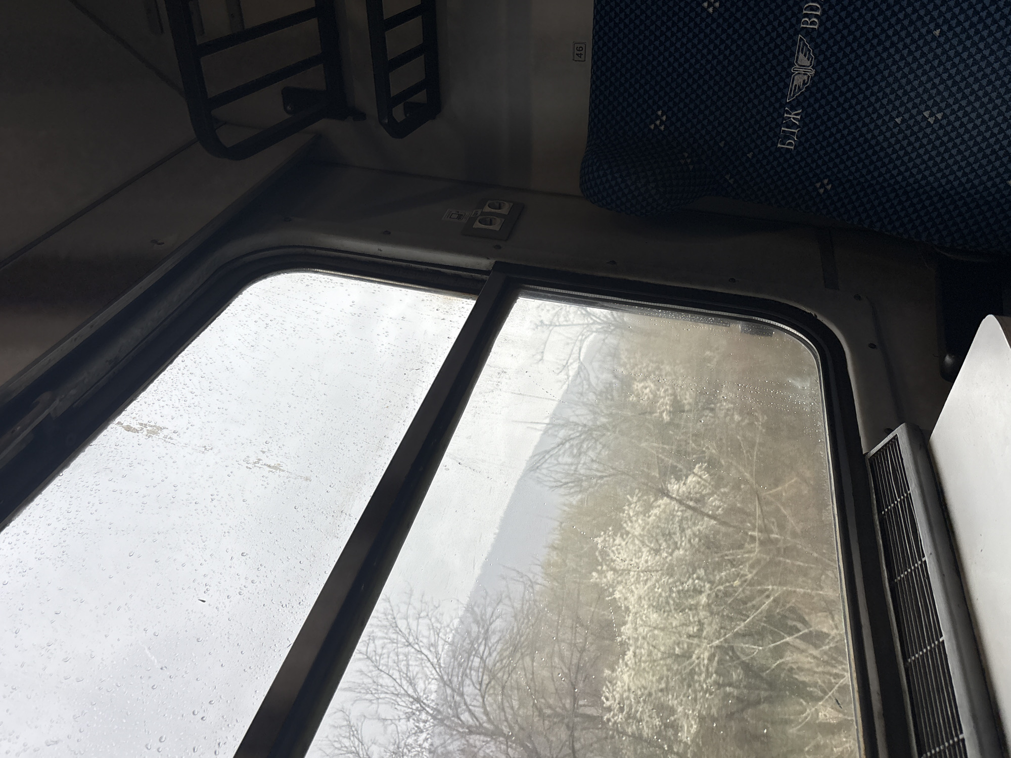 Rainy train journey through Bulgarian countryside with spring blossoms