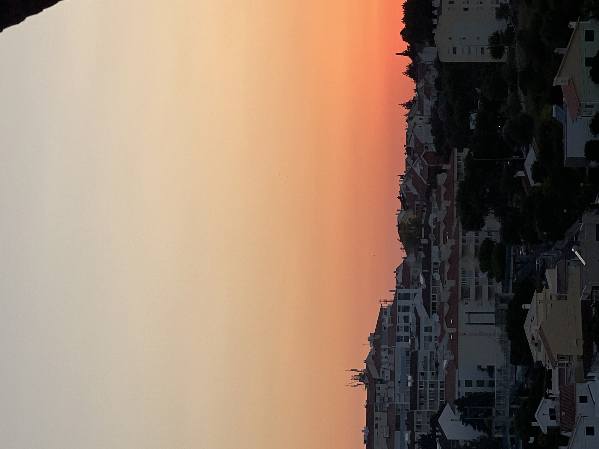 Cascais rooftops glow under a vivid summer sunset