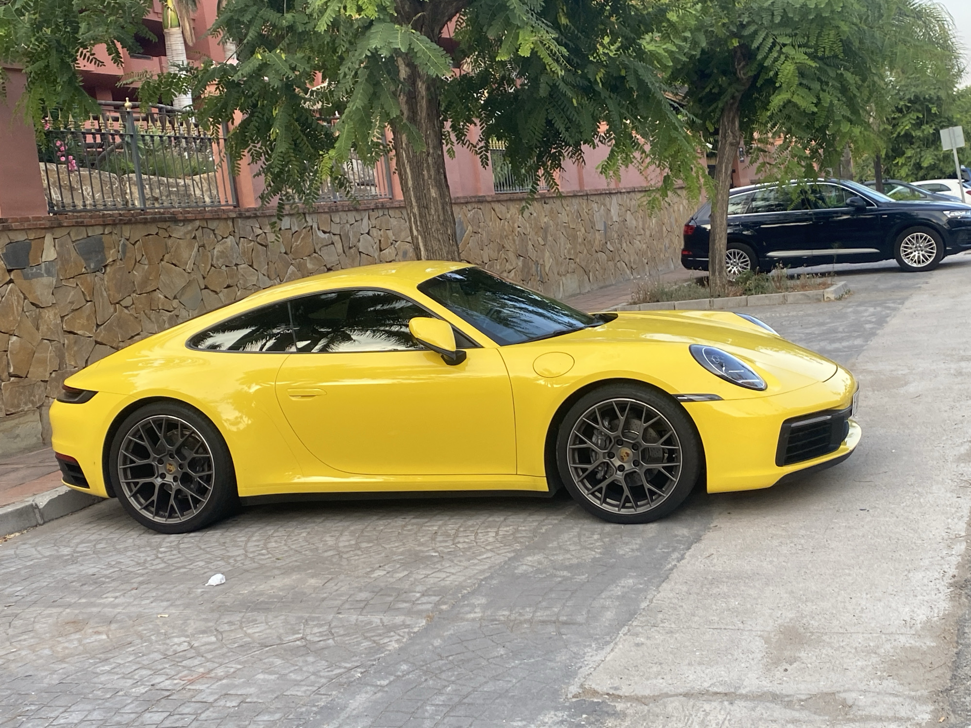 Yellow Porsche 911 parked on cobblestones in Estepona