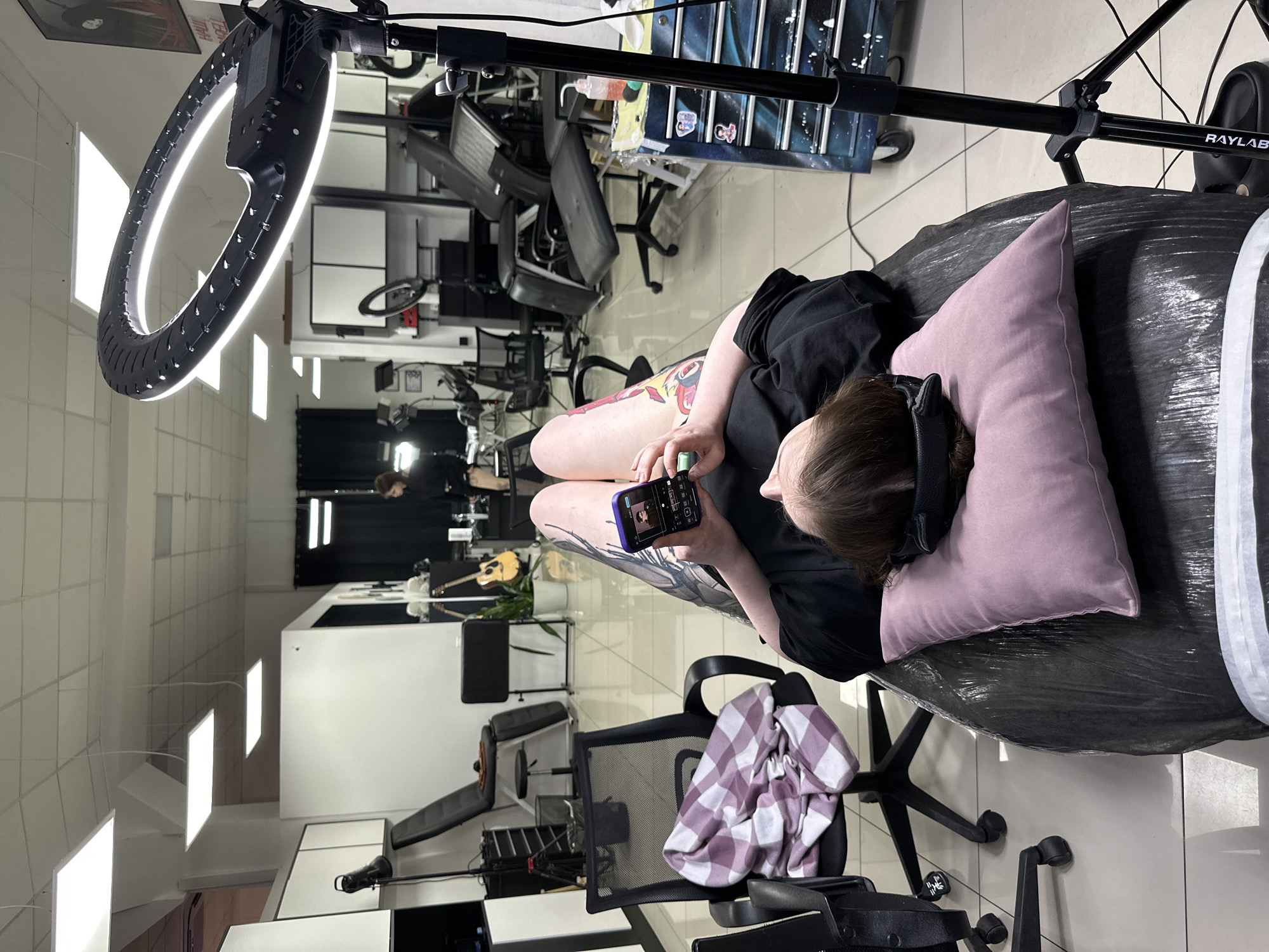 Person gets tattooed while using phone in Rostov studio