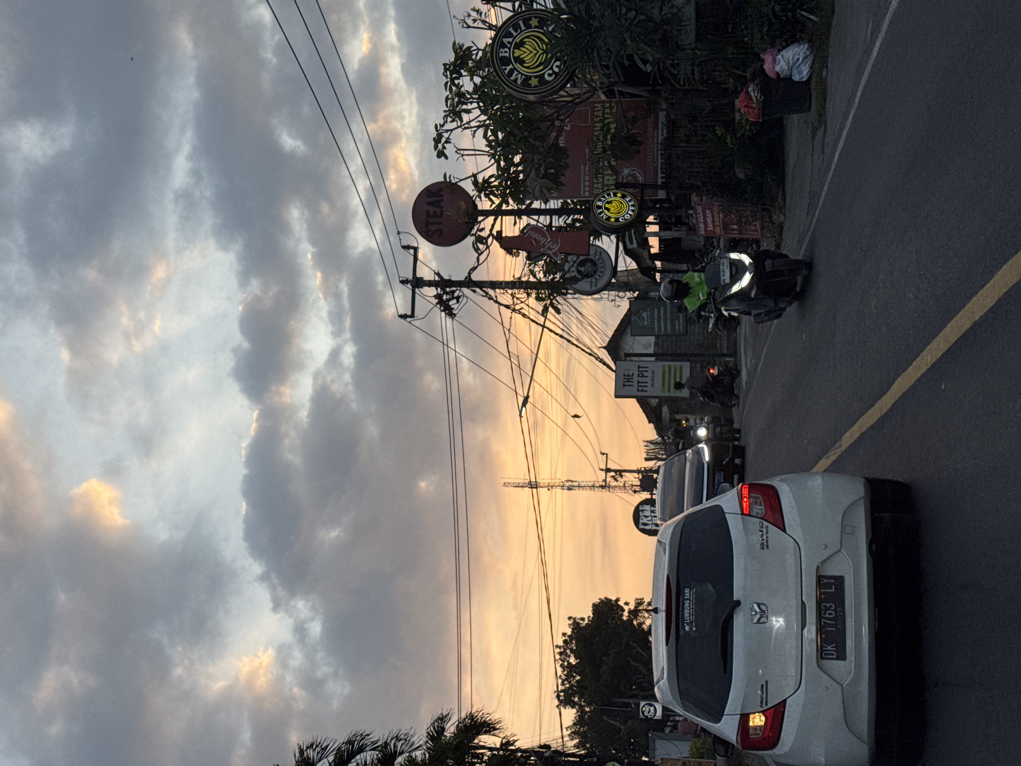 Dusk traffic on a Southeast Asian street, delivery riders in the flow
