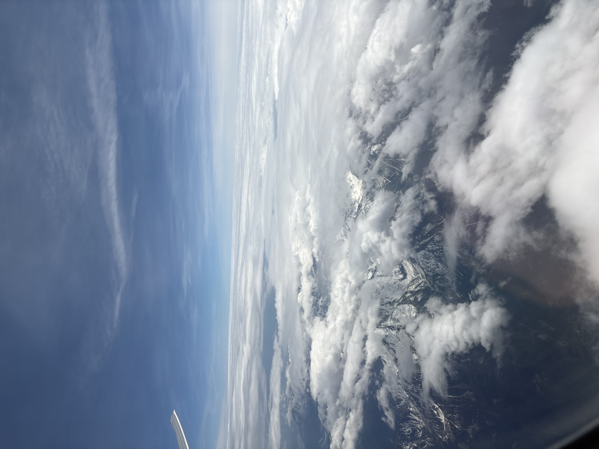 Aerial view captured from airplane window over mountains and clouds