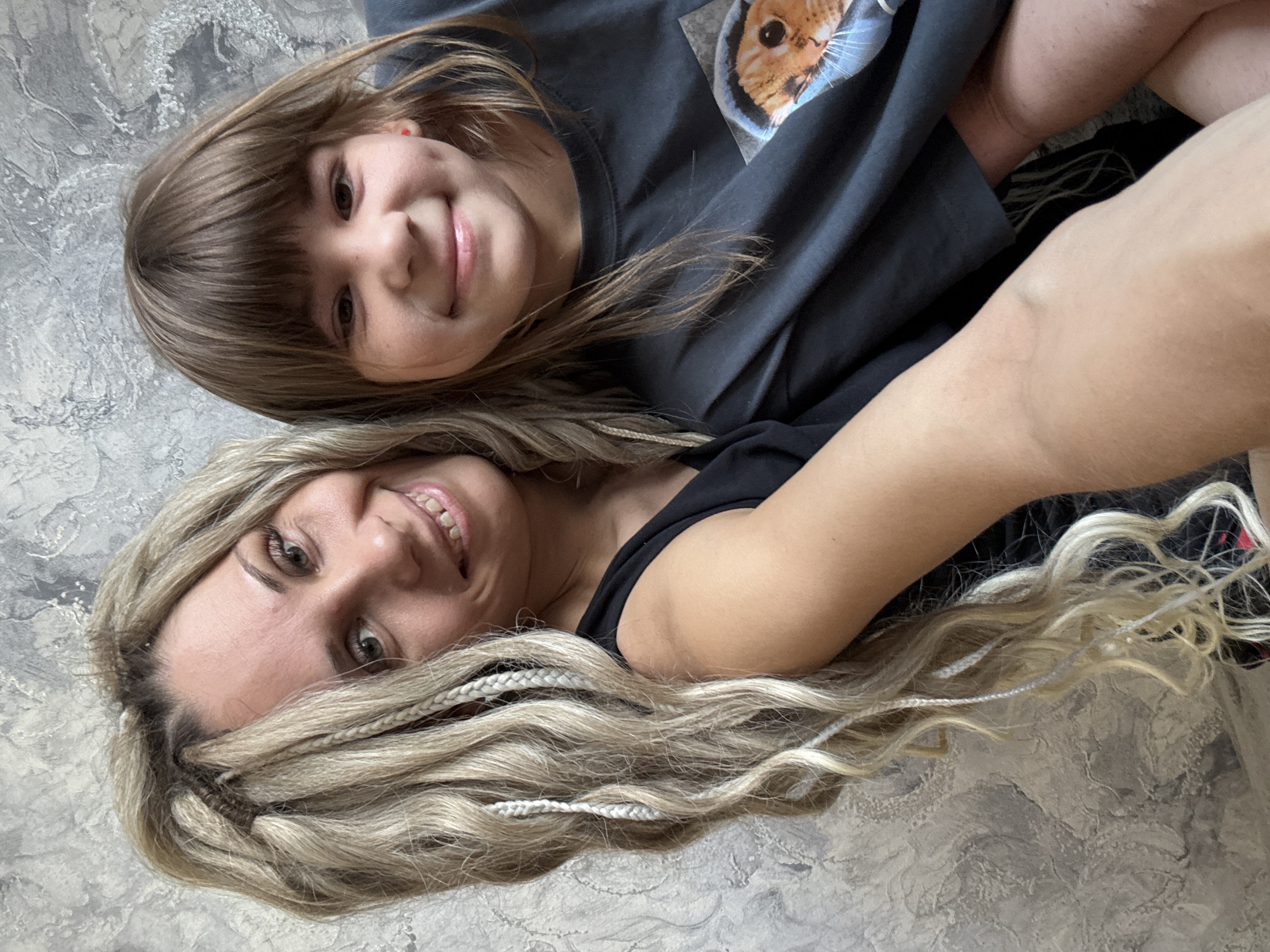 Two people photographed resting on gray surface