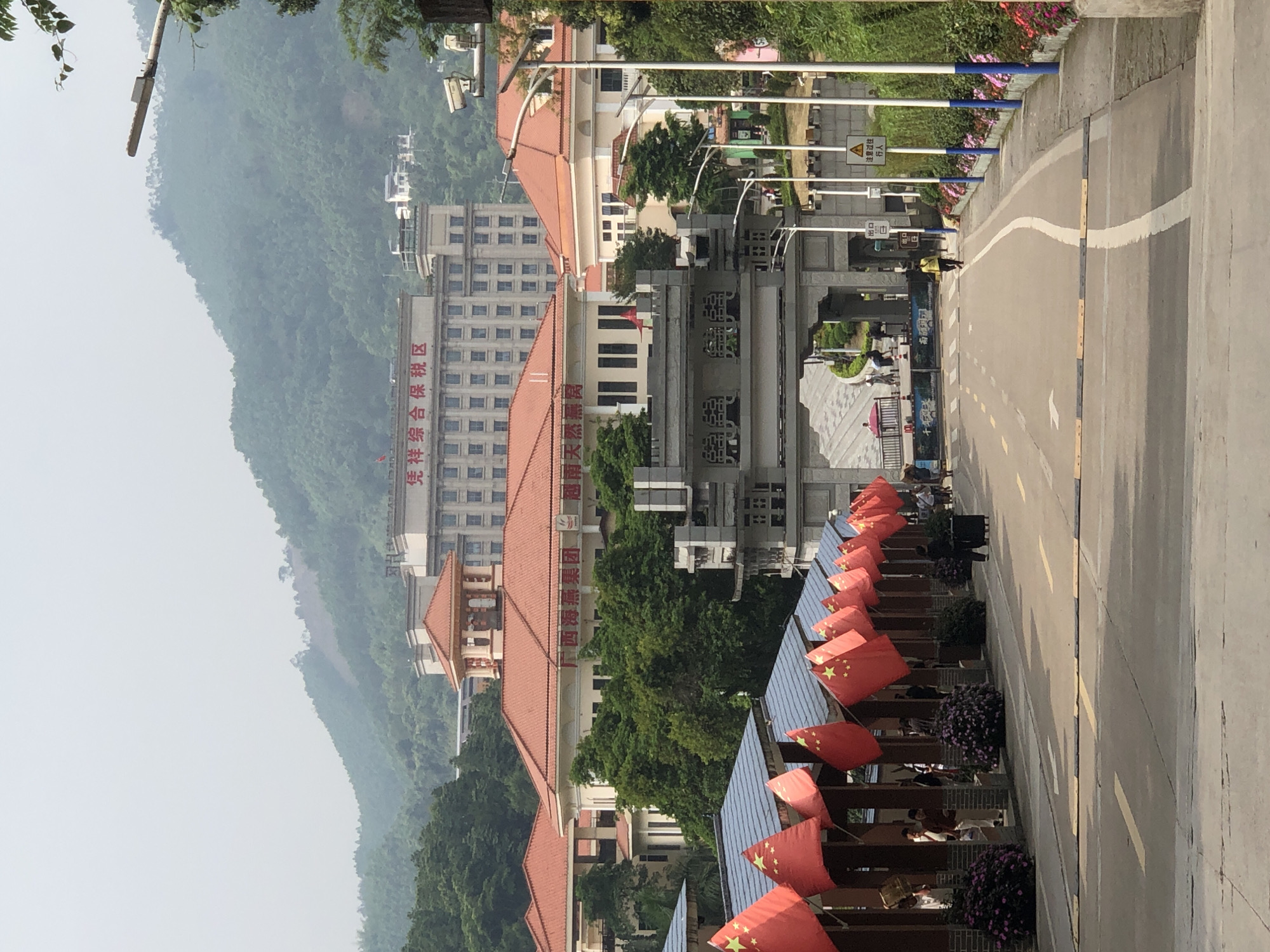 Morning pedestrians with luggage walk past flag displays in Quli