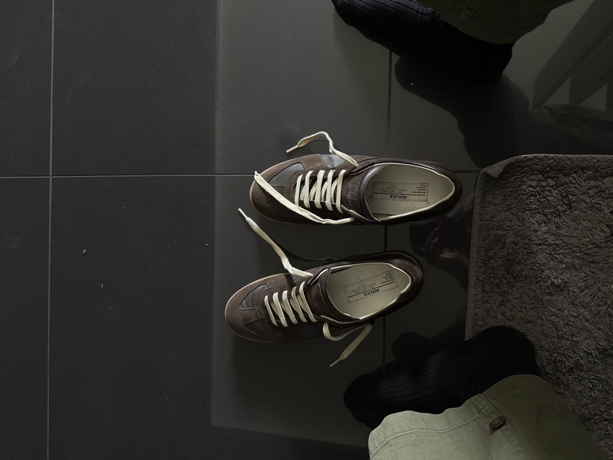 Brown suede sneakers spotted on dark tiles in London