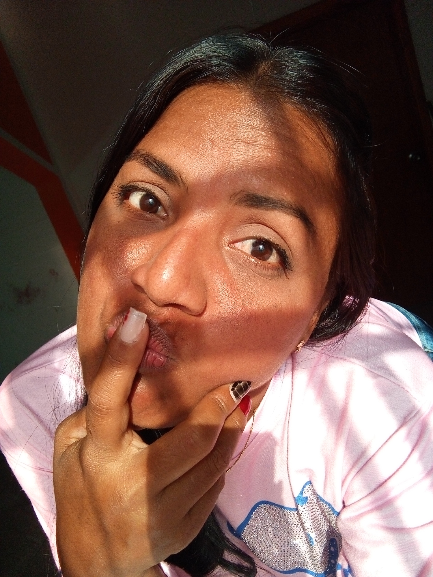 Woman poses for selfie with finger-to-lips gesture