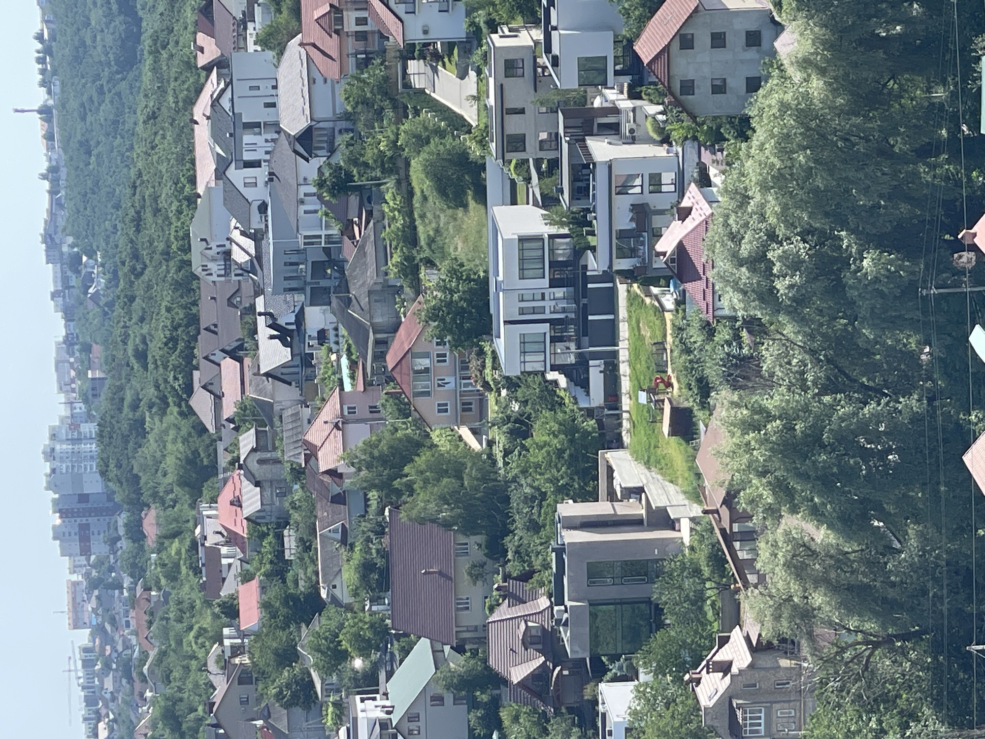 Aerial views of a hillside neighborhood with forest edge and local streets