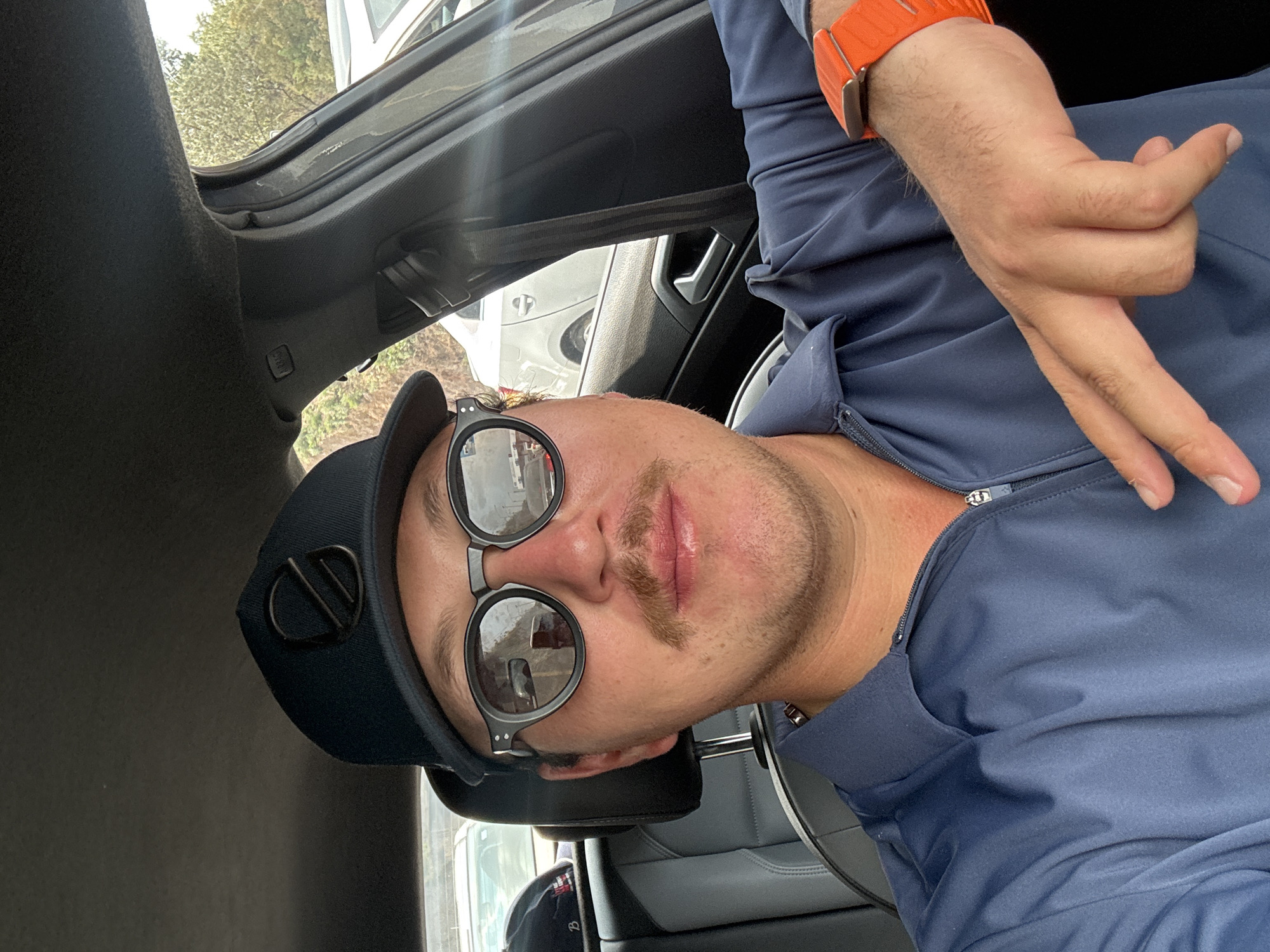 Man in navy cap makes peace sign in car