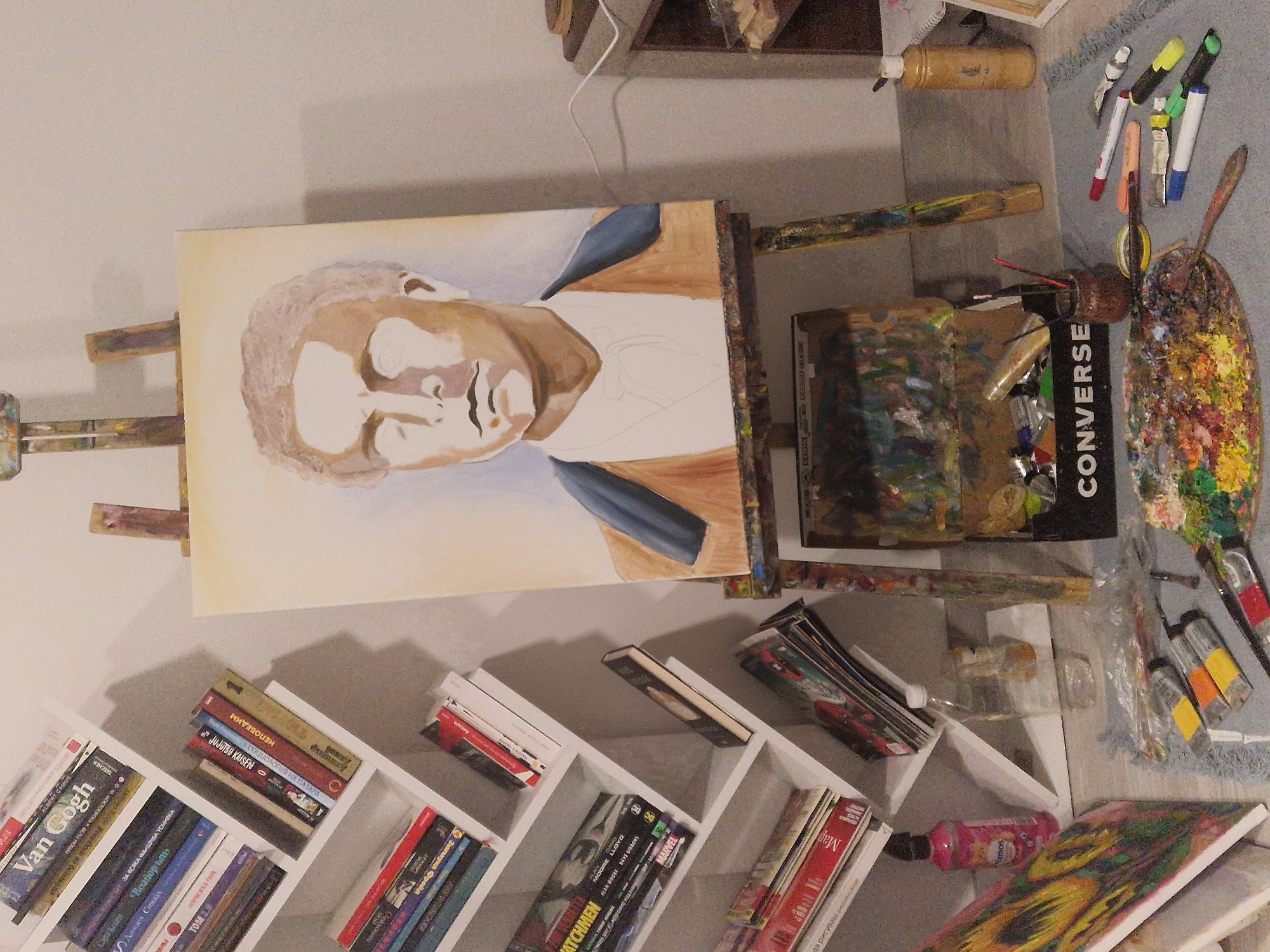 Artist works on unfinished male portrait in studio workspace