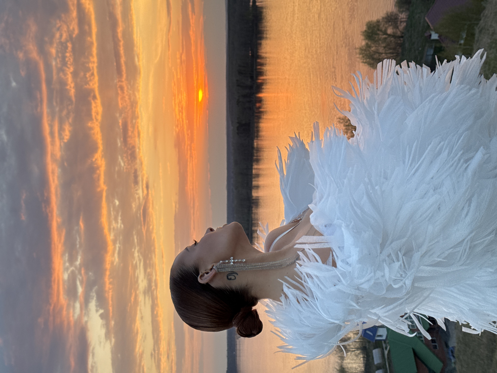 Woman in white feathers gazes skyward in Ольховка