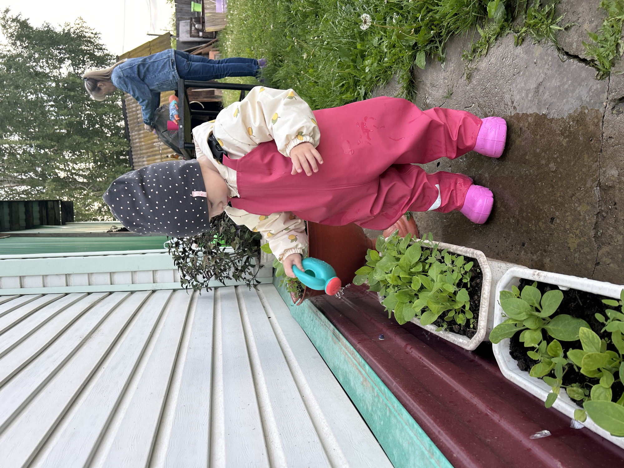 Toddler plays outdoors in rain gear in Азинский, Russia