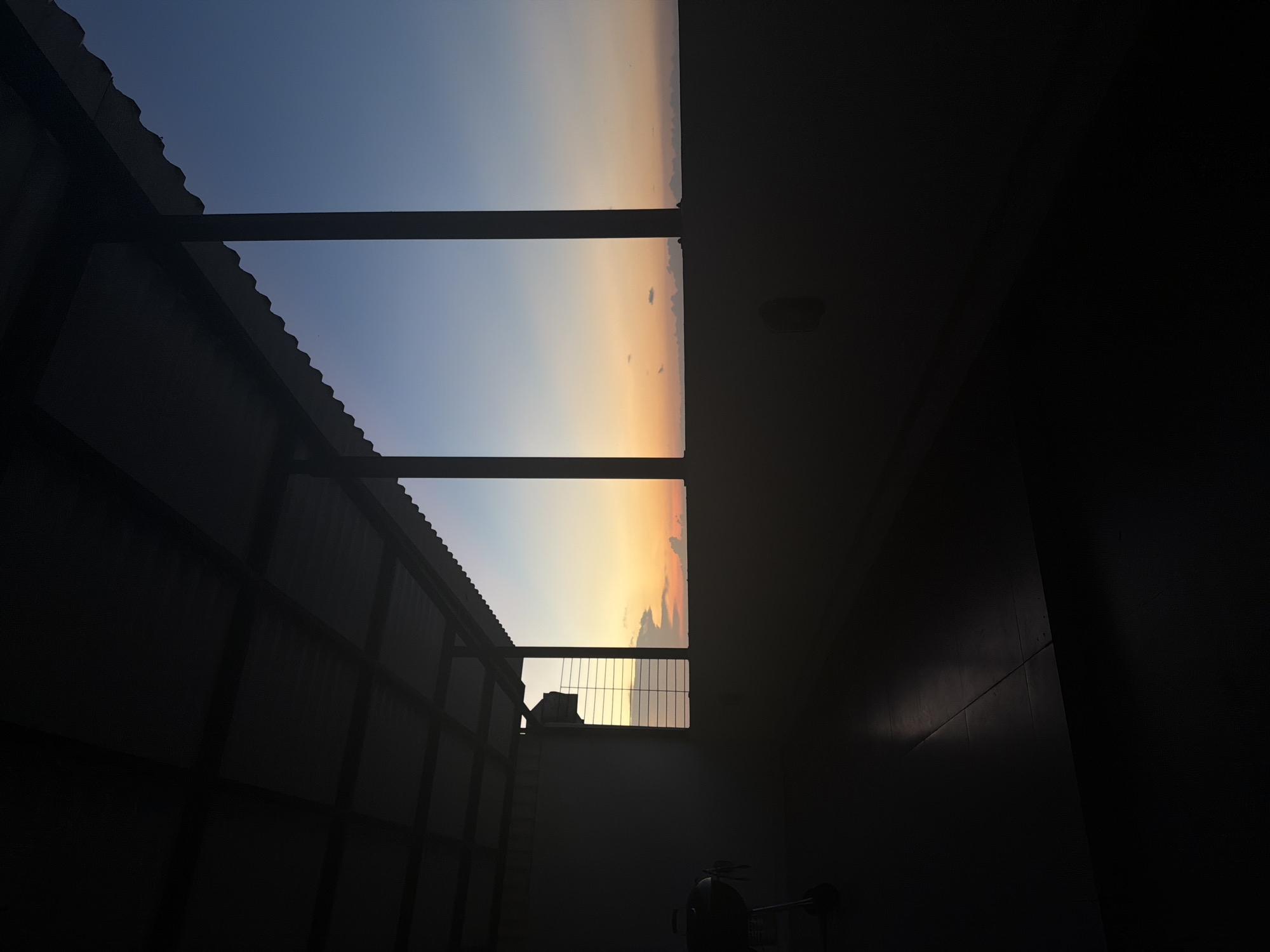 Sunset observed from balcony through corrugated roof structure