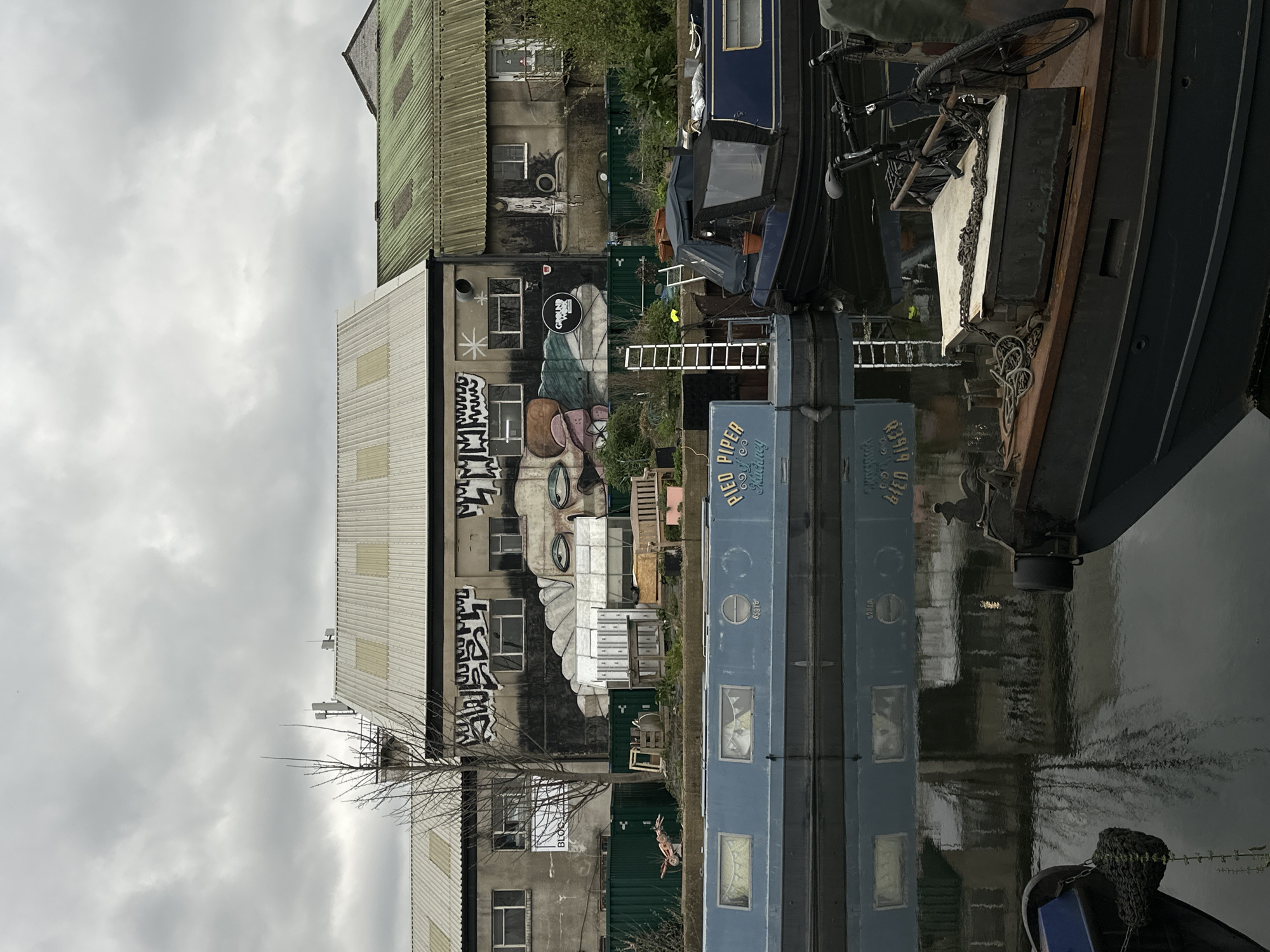 London canal scene features industrial building with face graffiti
