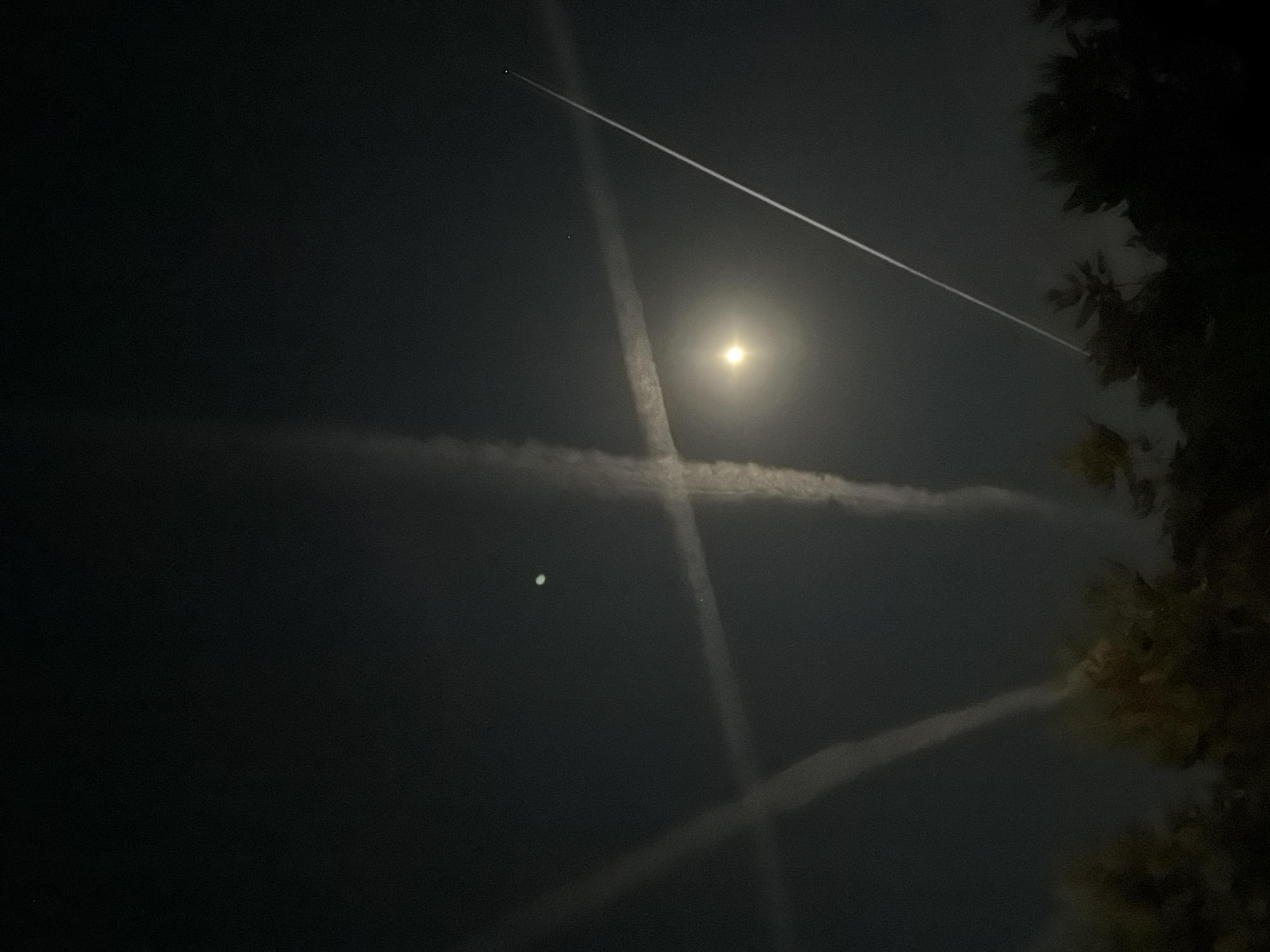 Intersecting aircraft contrails form X-patterns over Mishutkino night sky