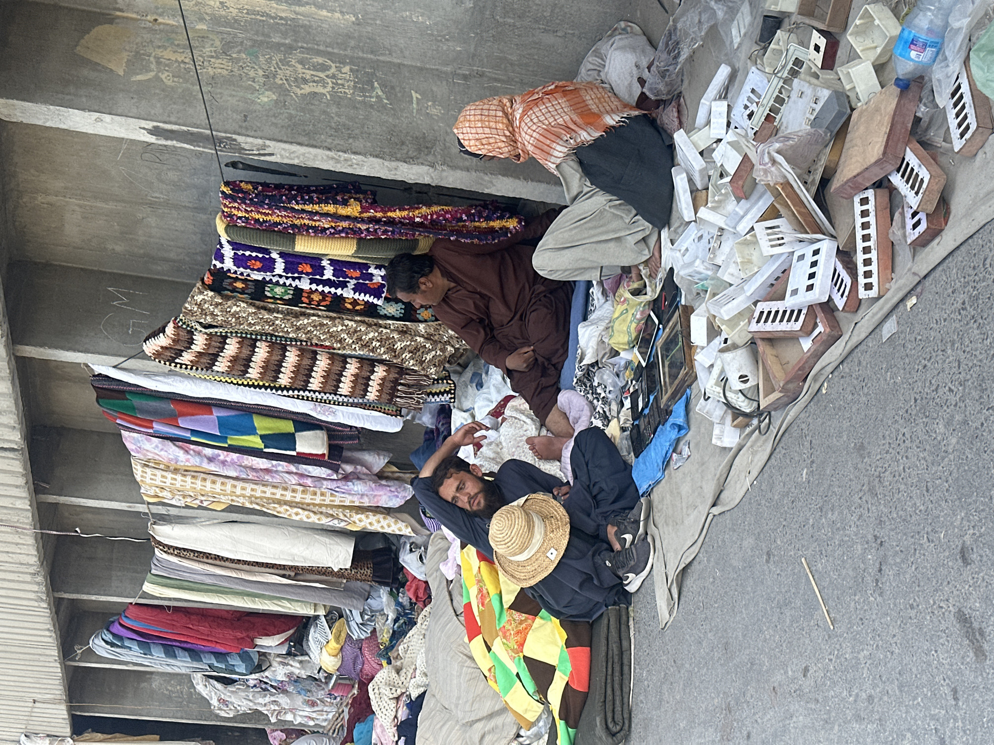 Street vendor rests as shopper passes Quetta market stalls