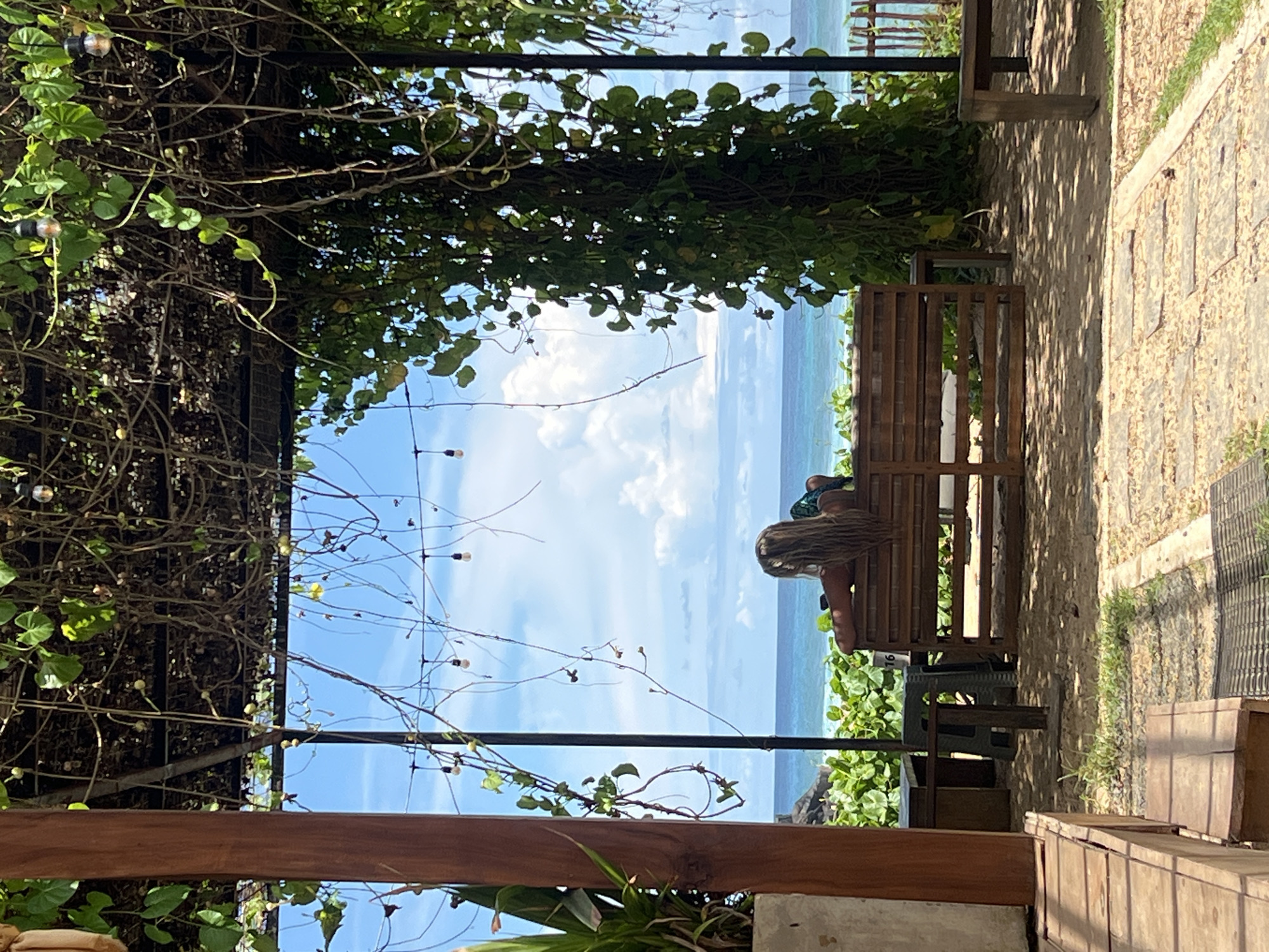 Person sits on bench overlooking ocean in Goviyapana, Sri Lanka