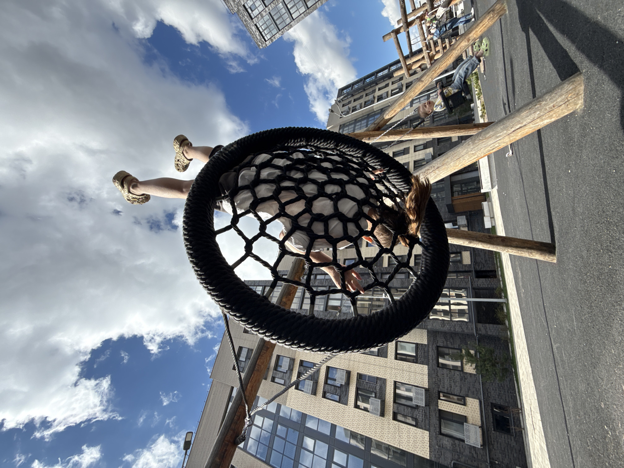 Child plays on basket swing in urban playground