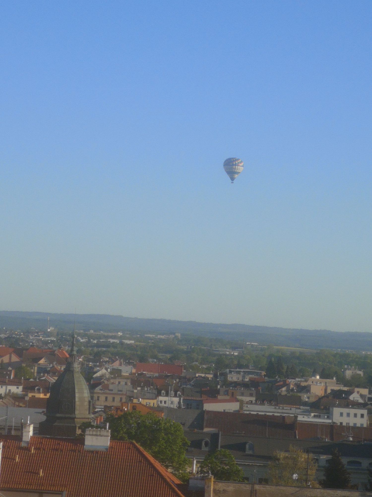 Hot air balloon ascends over Pardubice under clear skies