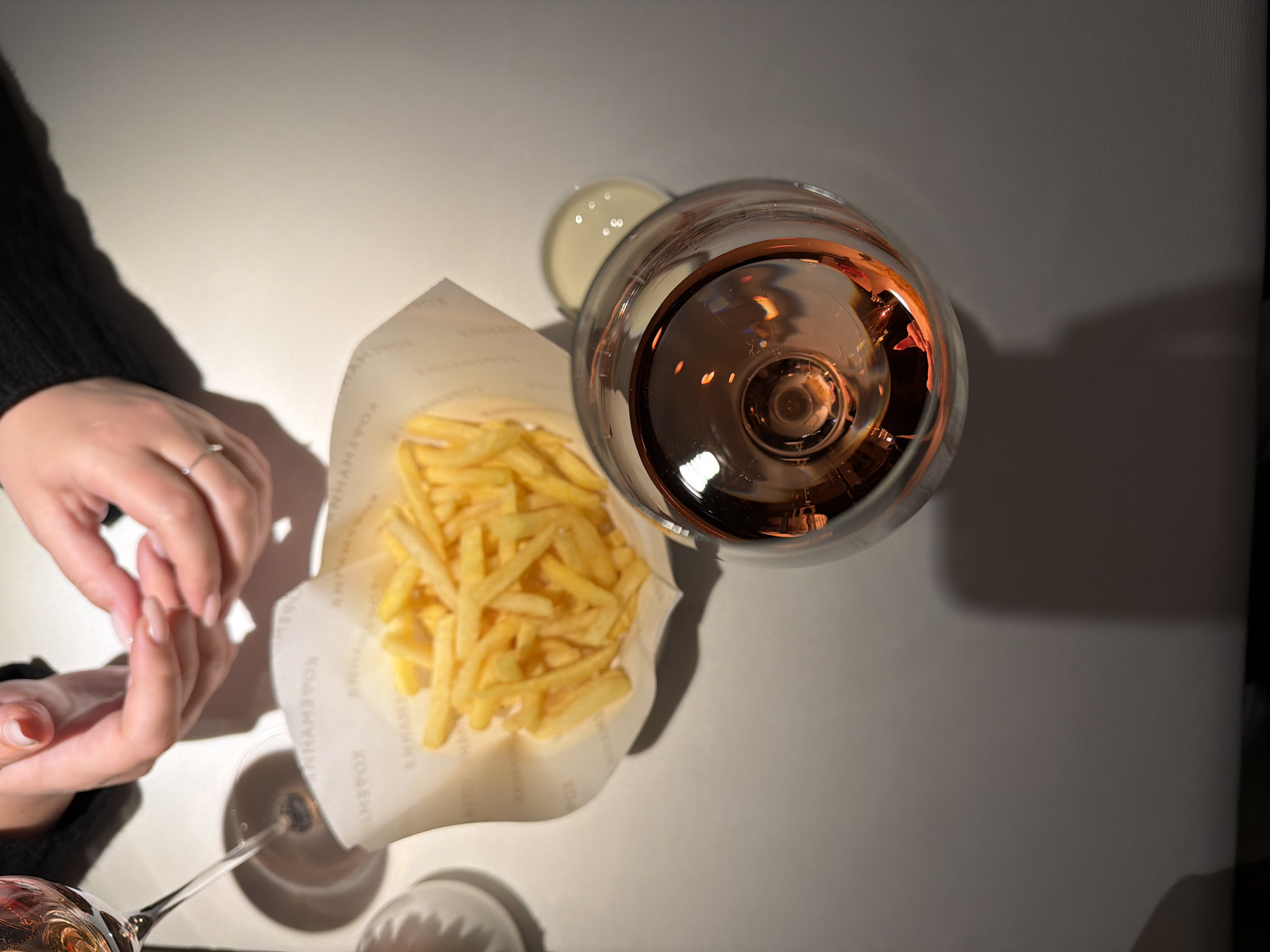 Diner enjoys fries and rosé wine at restaurant