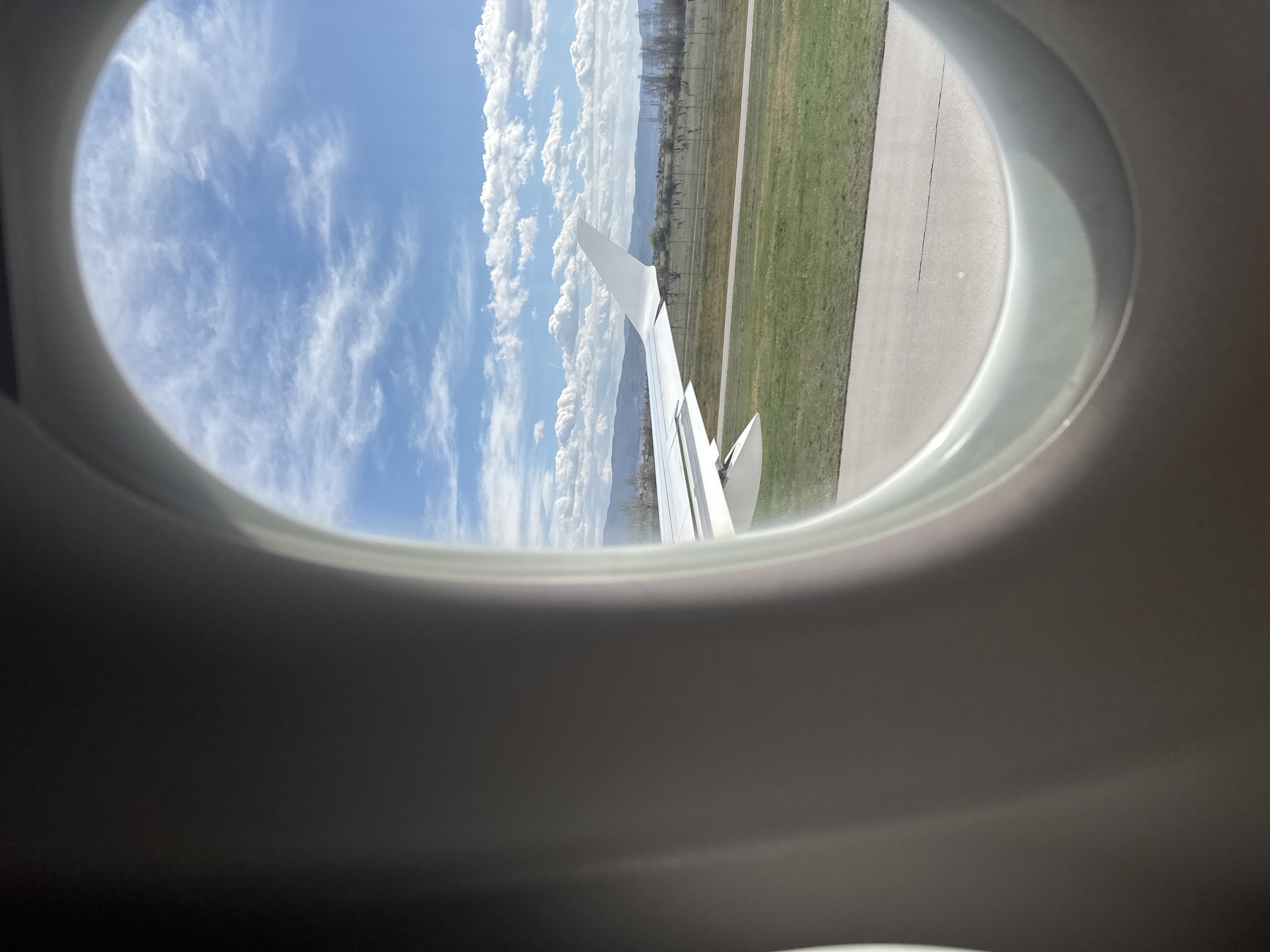 Airplane window view captures Sofia landscape with mountains, runway